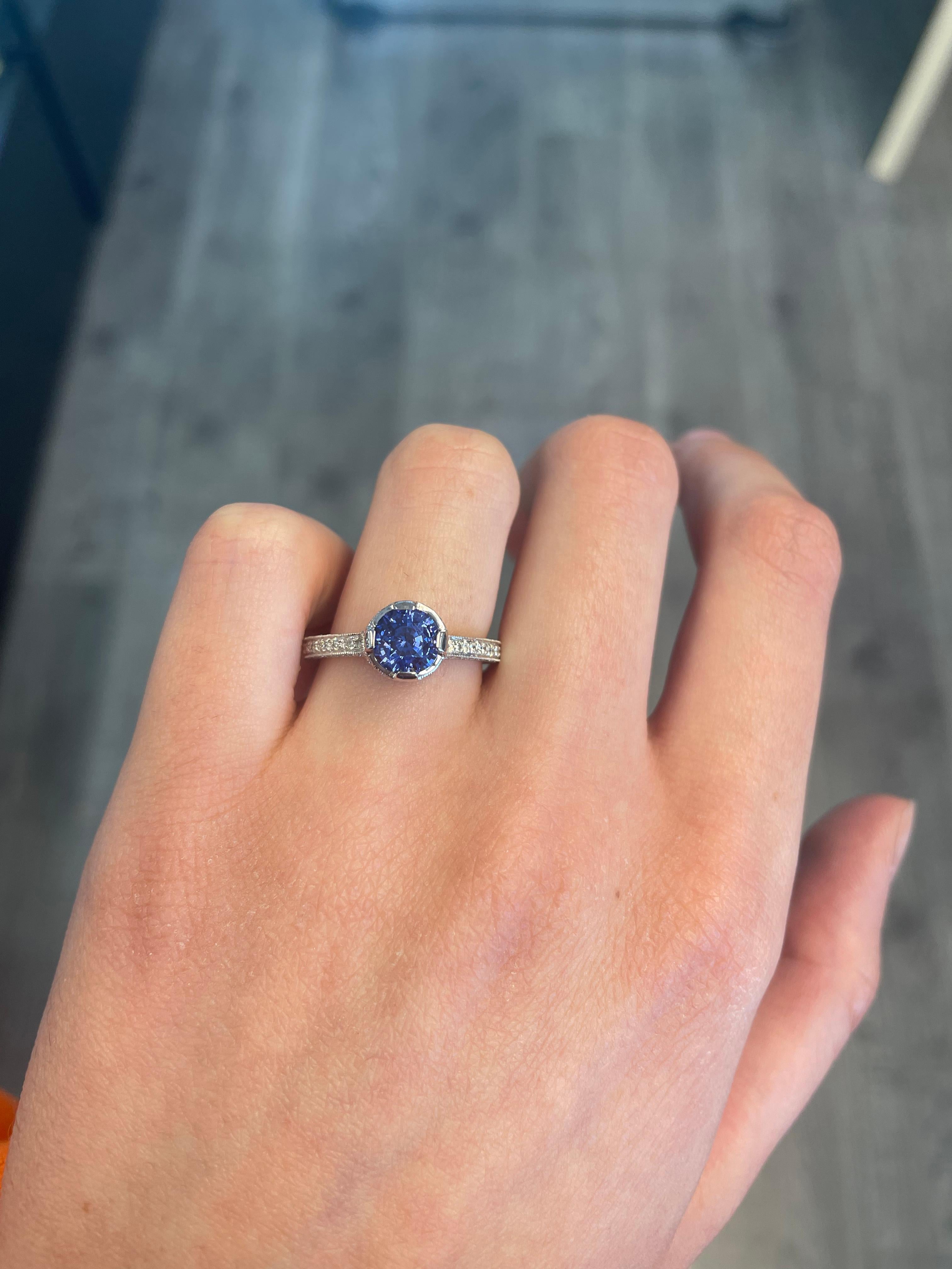 Art Deco style round Ceylon sapphire ring with diamonds.
2.27 carats total gemstone weight.
Center 1.56 carat round Sri Lankan sapphire, heat. Complimented with 0.71 carats of round brilliant diamonds, approximately G/H color and SI clarity. 18k