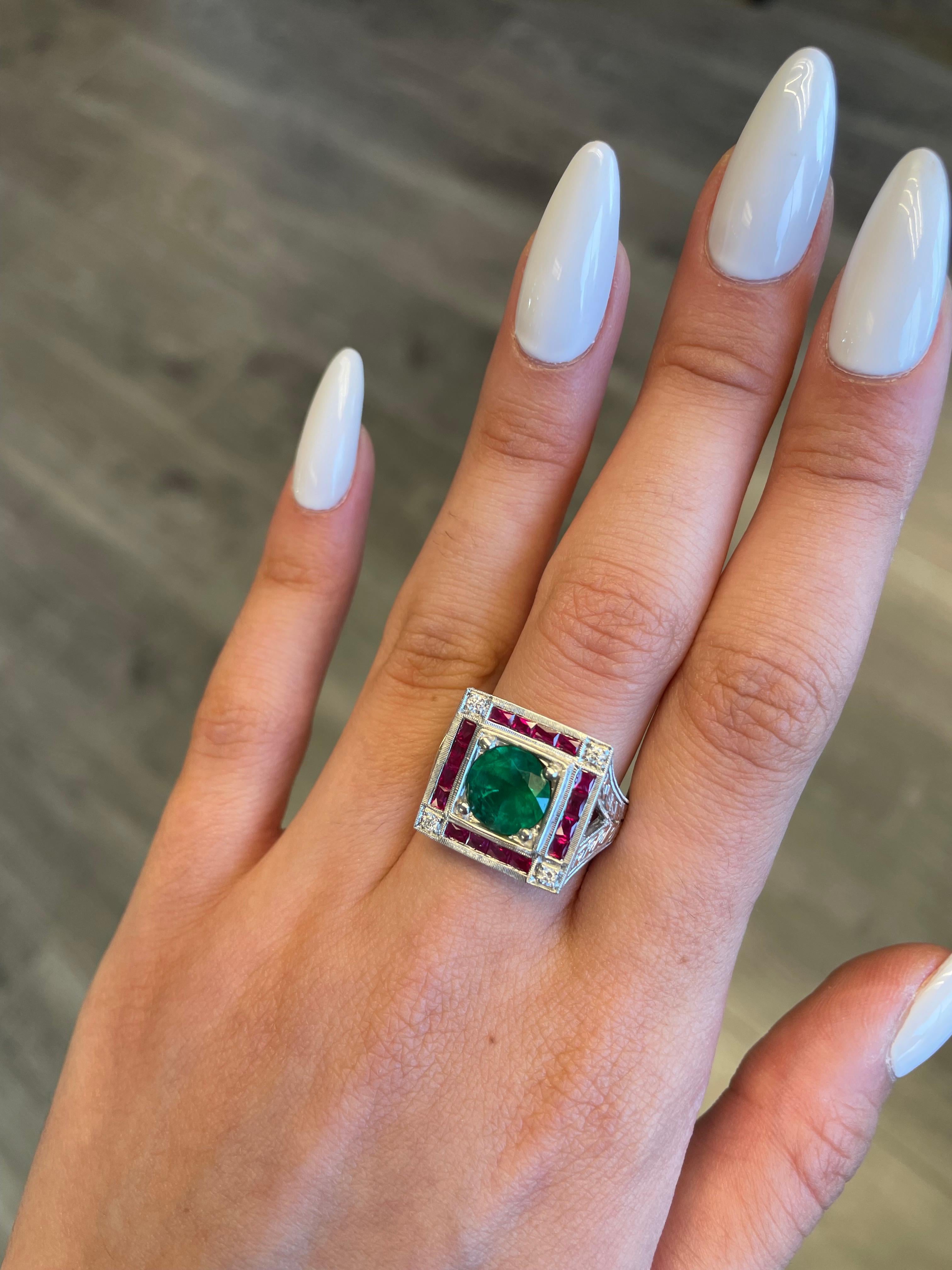 Lovely vintage inspired emerald with sapphires and diamond ring.
2.88 carat round emerald apx F2 complimented with 1.20ct of french cut rubies heat and 0.10ct of round brilliant diamonds. Approximately G/H color and SI clarity. 18-karat white gold