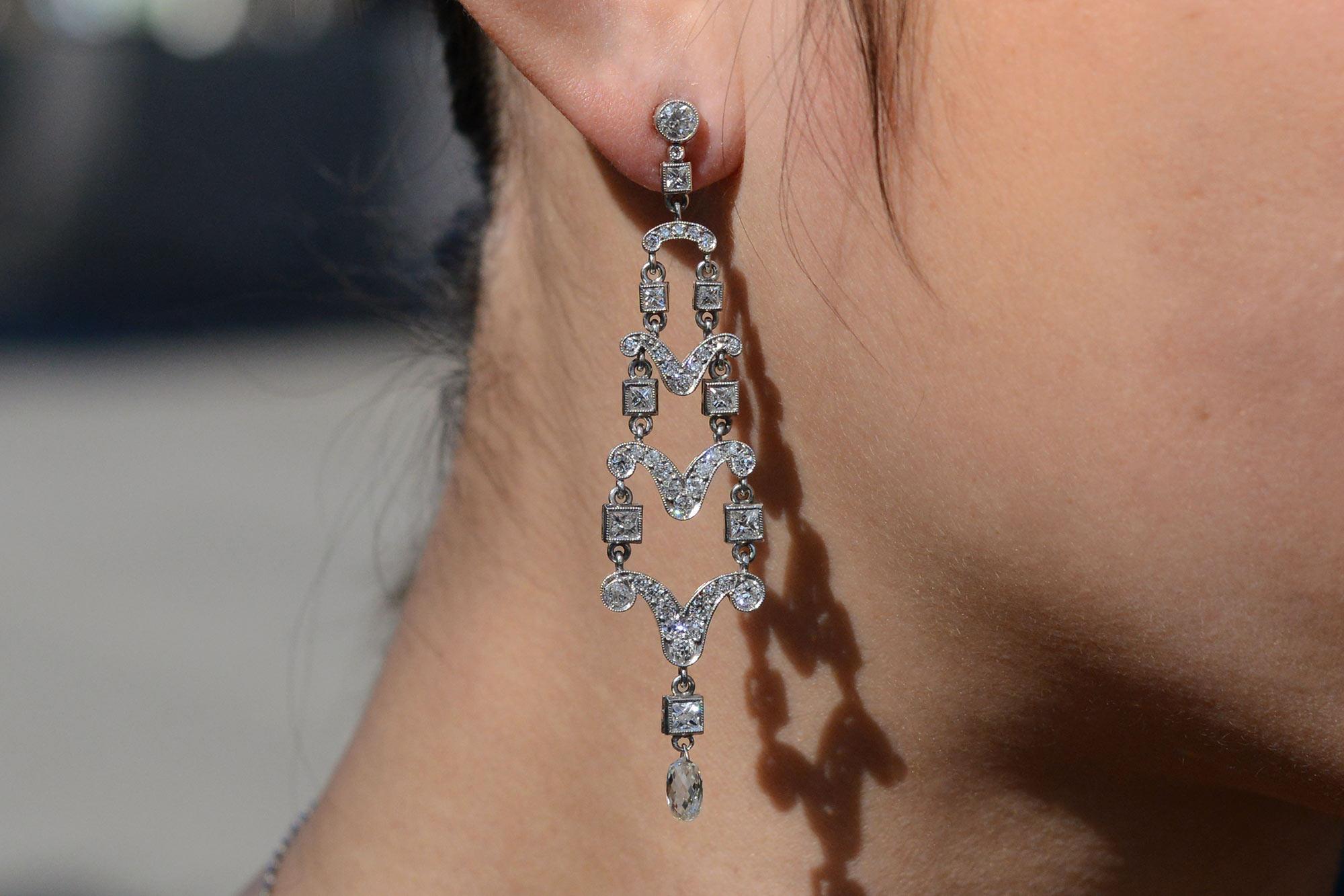 This magnificent pair of chandelier earrings deliver the sparkle with 4 carats of dazzling diamonds. Showcasing scrolls of diamonds partitioned by individual princess cut diamonds draped on either side. Concluding with a single briolette cut diamond
