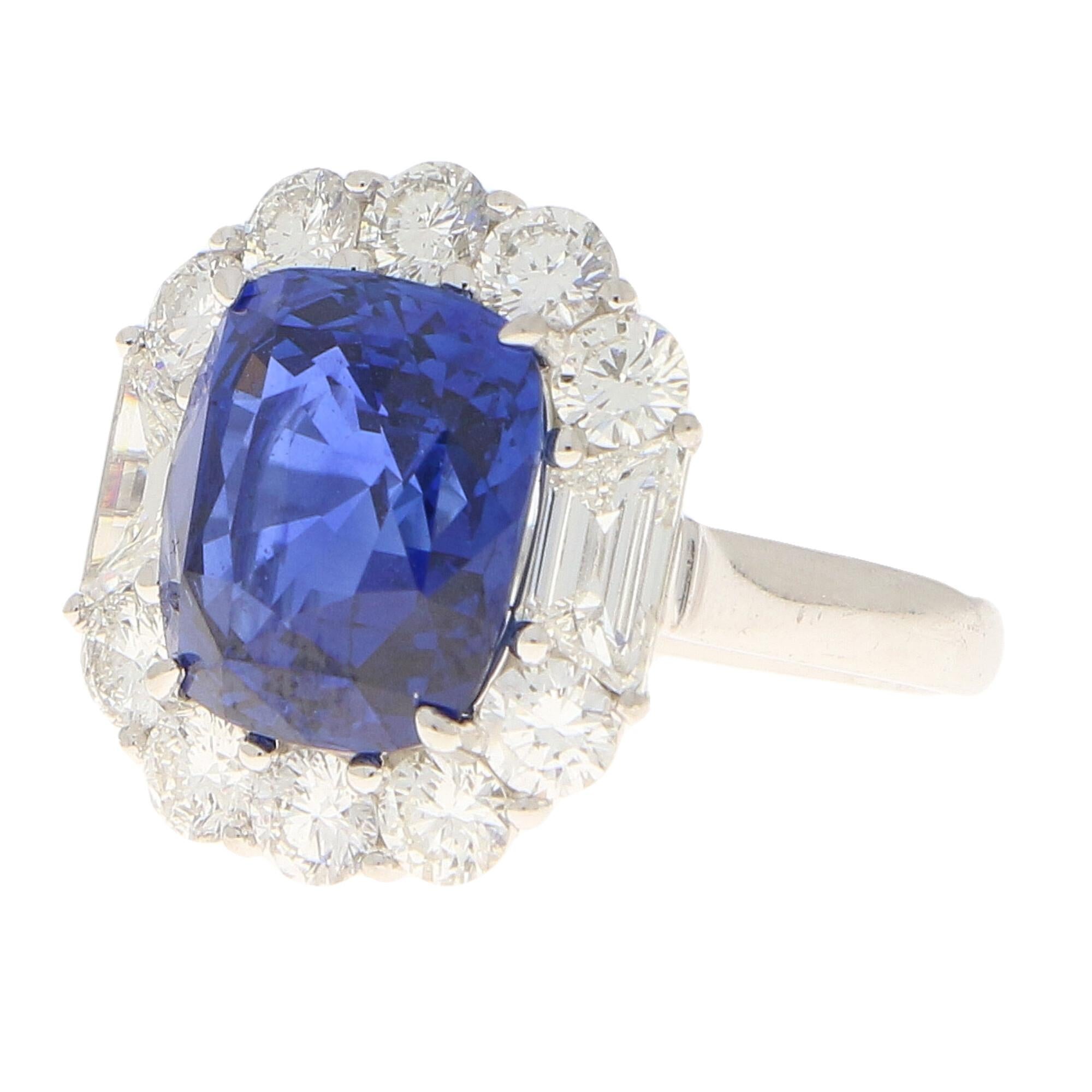 A truly stunning Art Deco inspired sapphire and diamond cluster ring set in platinum.

The piece is centrally set with an astounding 7.62 carat royal blue cushion cut sapphire which is securely four-claw set in platinum. The sapphire has a desirable