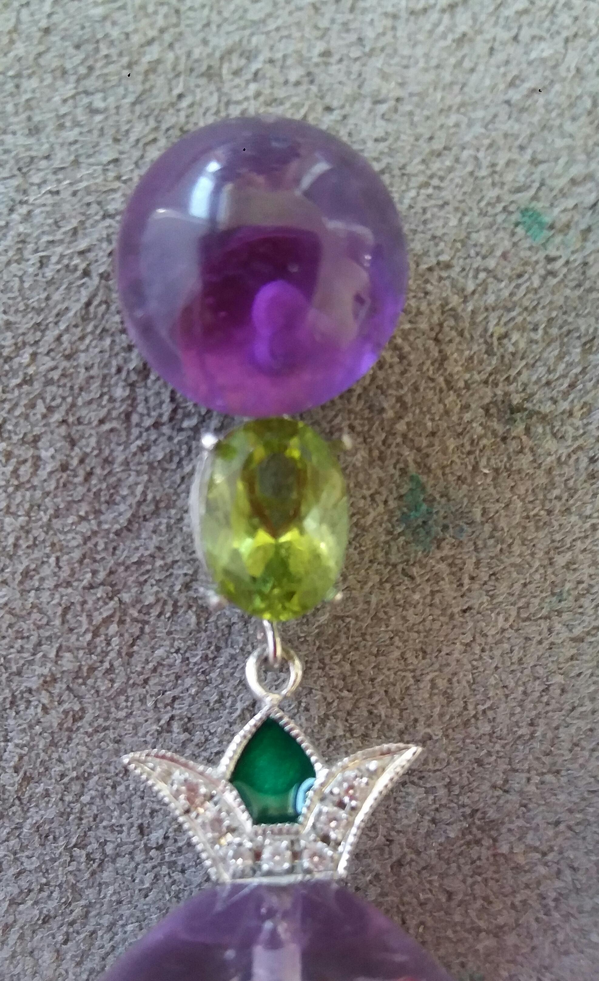 The upper part is composed of 2 amethyst buttons 10 mm diameter. from which are suspended  a pair of faceted peridots and 2 elements in white gold diamonds and green enamel, at the bottom we have 2 large Amethyst round drops measuring 17 x 18