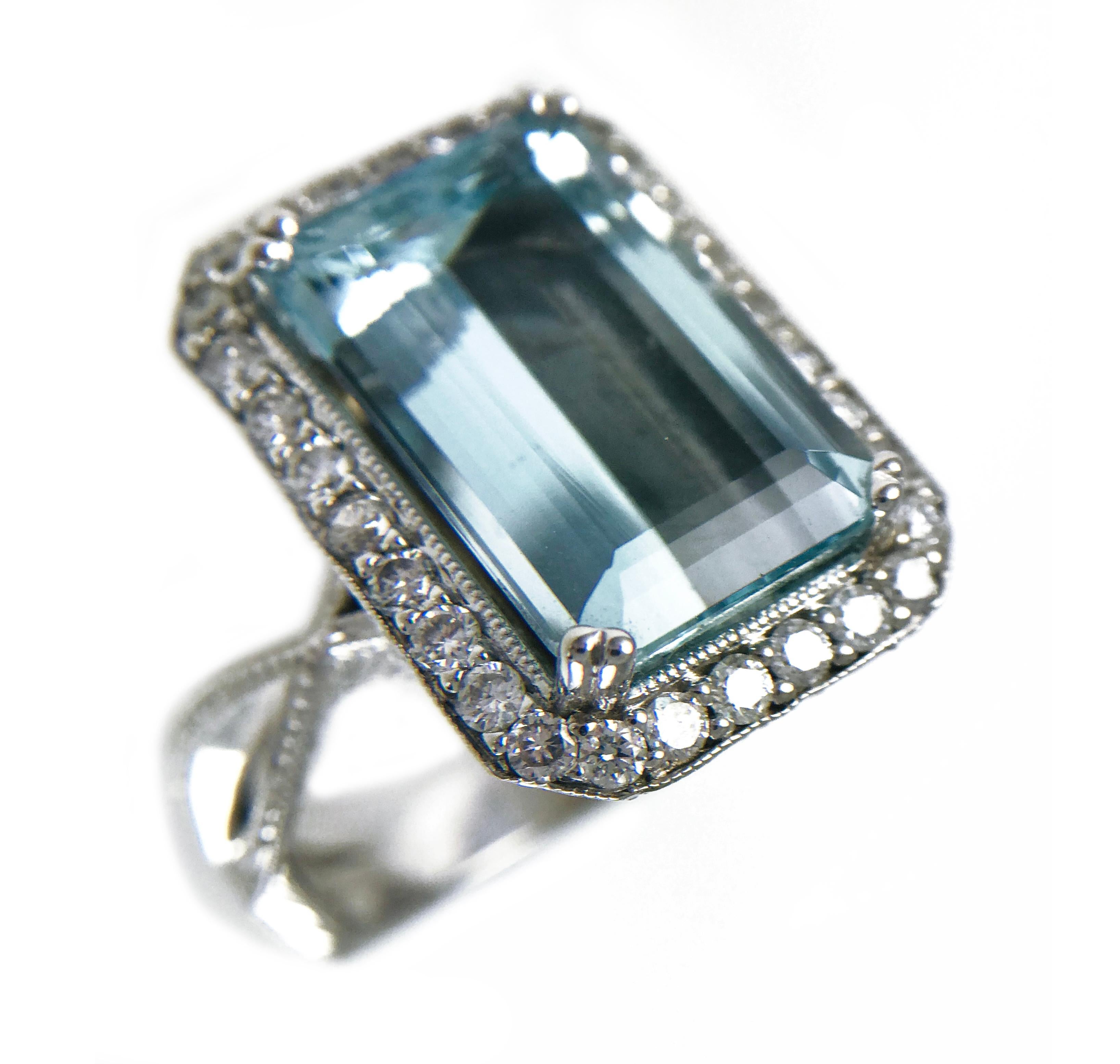 14 Karat White Gold Emerald-Cut Aquamarine Ring with milgrain detail and bead-set Diamond surround. The center Aquamarine gemstone is set in an enclosed mirrored mounting and measures 15mm x 9.7mm. The Aquamarine has a carat weight of 6.72ct, the