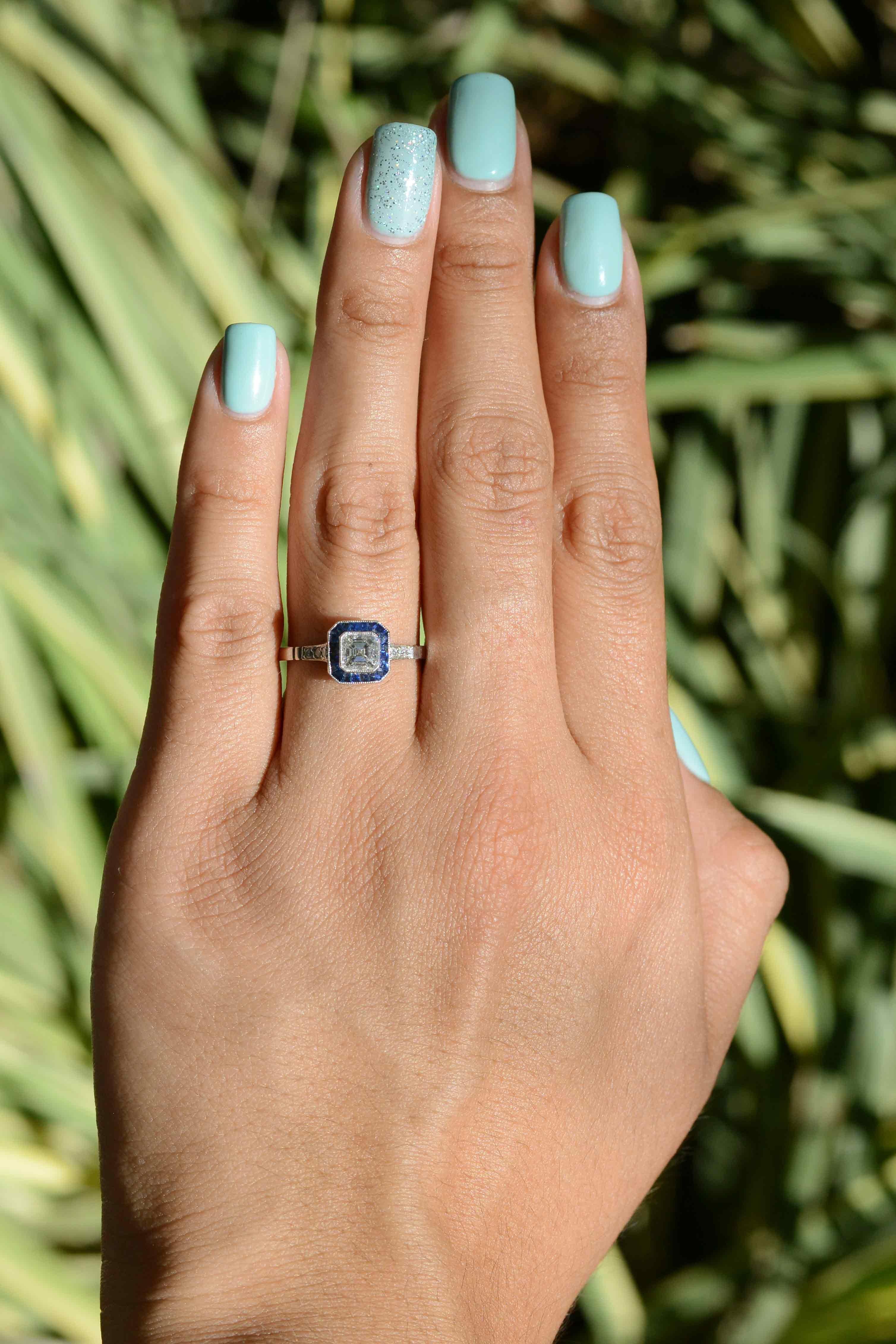 Ein atemberaubender, vom Art Deco inspirierter Verlobungsring aus Platin mit Diamanten und Saphiren. Ein einzigartiger Diamant im Asscher-Schliff, der sich durch seine unglaubliche Brillanz und sein Feuer auszeichnet und eine farblose (F) Einstufung