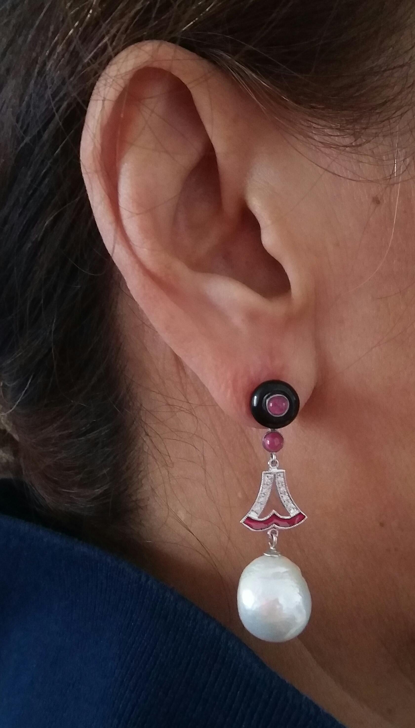 A pair of art deco style earrings, with an upper part consisting of 2 black onyx buttons with in the center 2 small round ruby cabochons, a central part where we have 2 elements in white gold, diamonds and red enamel,that support 2 white baroque