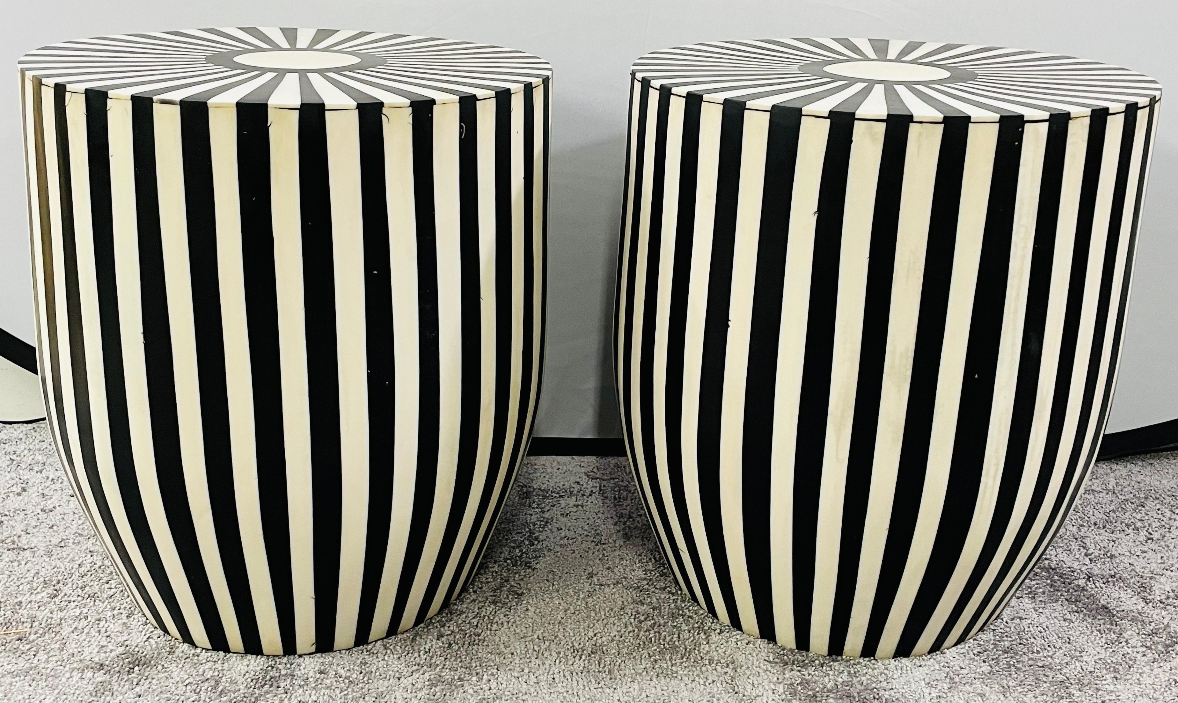 A one of kind pair of Art Deco style black and white side tables or stools featuring a striped design. The tables are made of quality resin and have a solid and sturdy structure. The sculptural cylindric shaped tables have a round top and and narrow