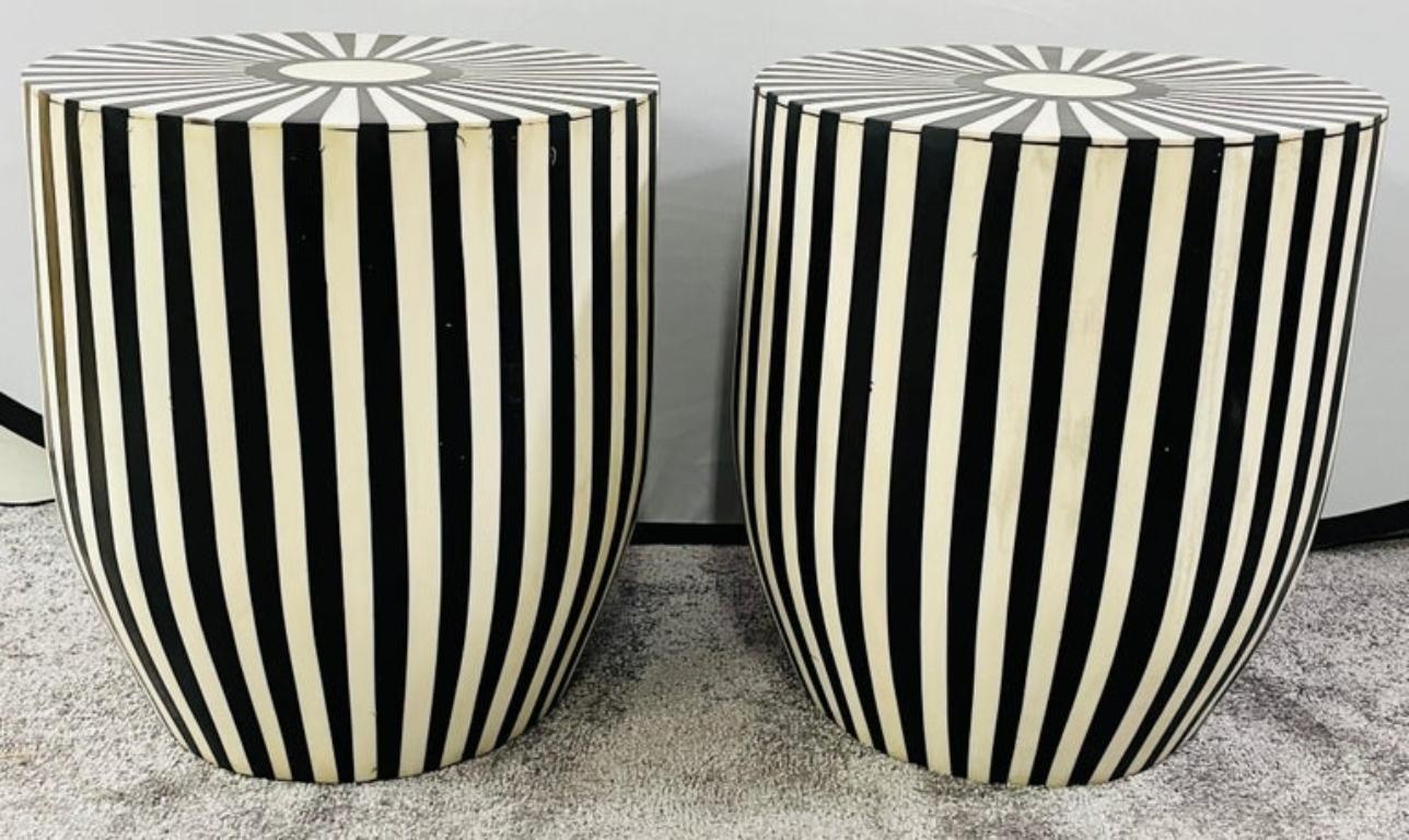 A one of kind pair of Art Deco style black and white side tables or stools featuring a striped design. The tables are made of quality resin and have a solid and sturdy structure. The sculptural cylindric shaped tables have a round top and and narrow