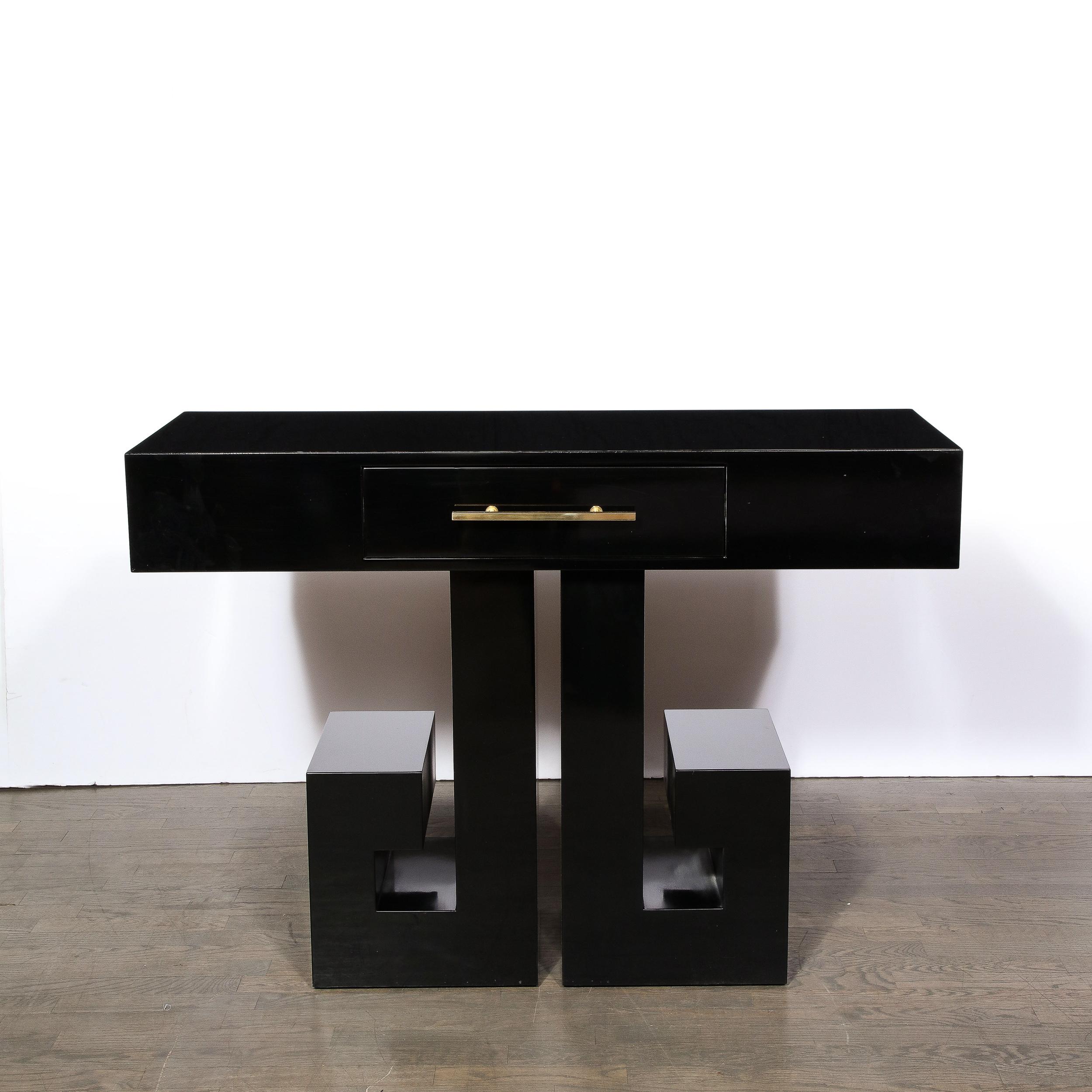 This elegant Art Deco style console table was realized in the United States during the 20th century. It features a sculptural base consisting of two stylized and abstracted Greek Key supports that wrap around and stop just short of completing an