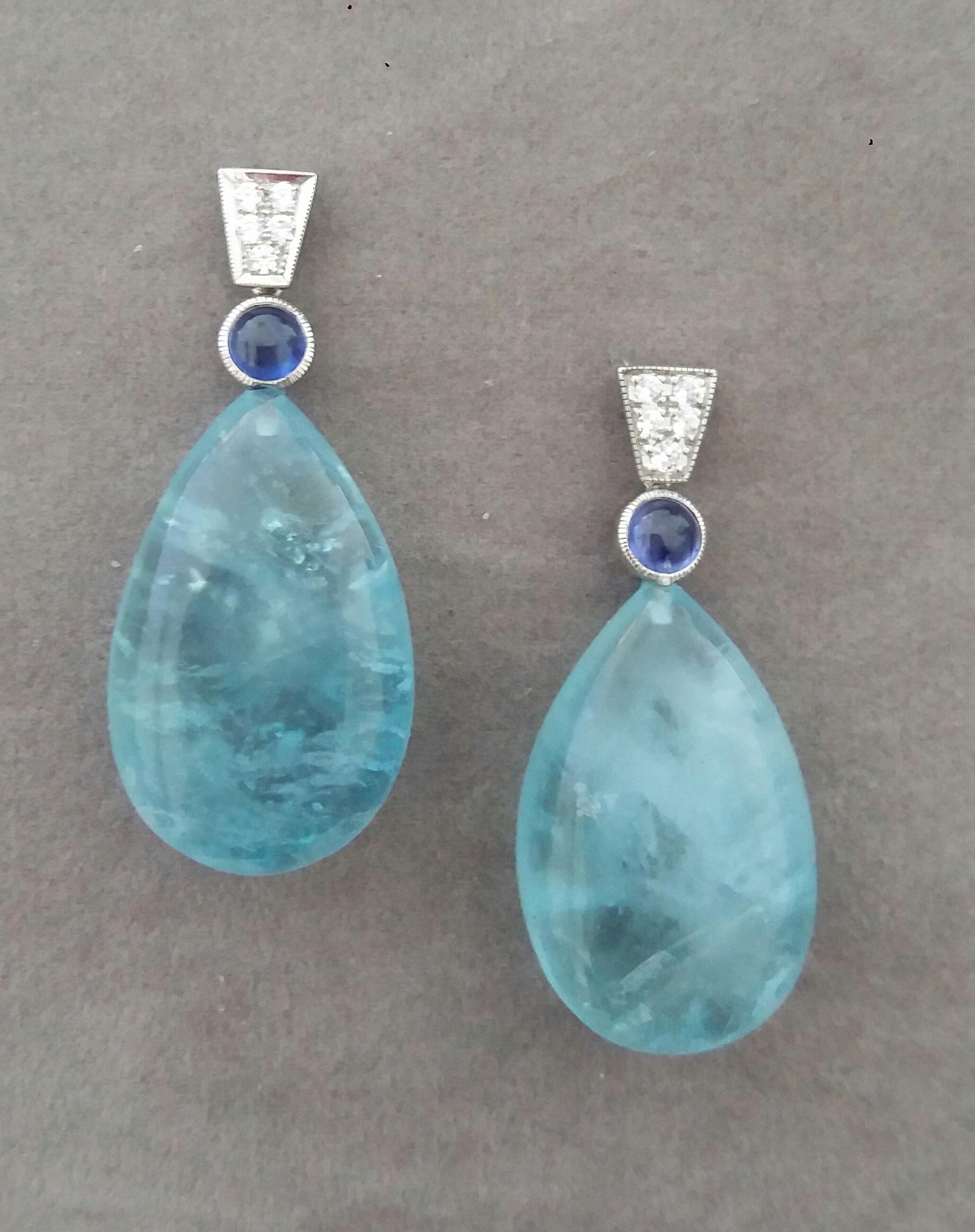 In these classic and chic Art Deco Style earrings the tops are 2 trapeze shape 14 kt.white gold parts with  10 round full cut diamonds and 2 Blue Sapphire round cabochons 5 mm in diameter,in the lower parts we have 2 Natural Aquamarine Plain  Drops 
