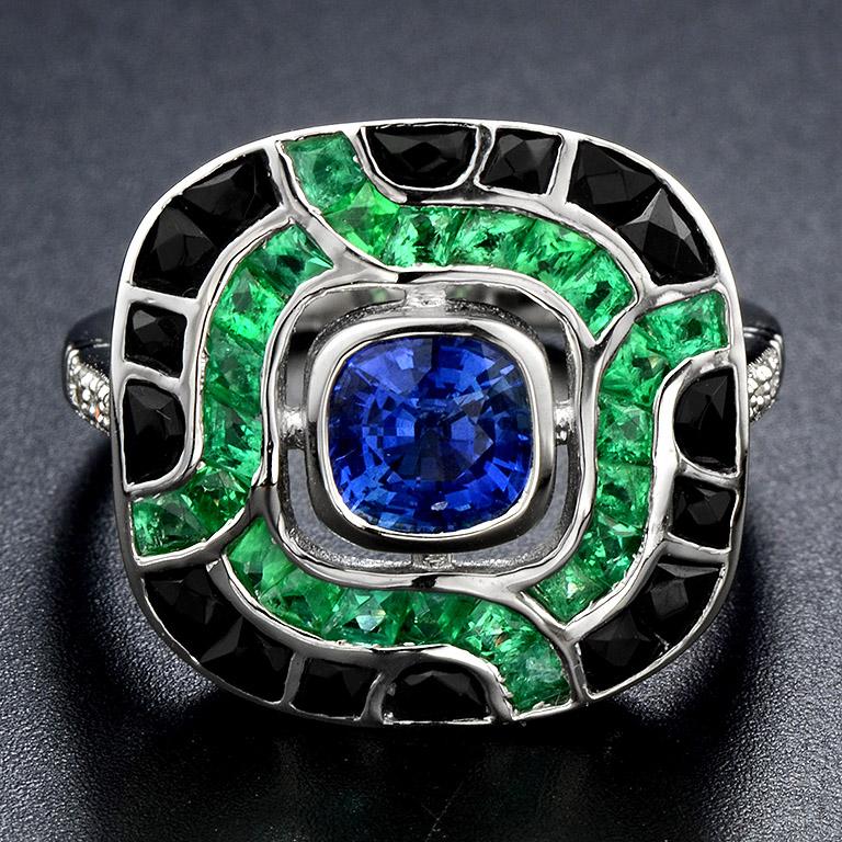 Magnifico anello da cocktail ispirato all'Art Déco. Questo splendido anello presenta uno zaffiro di Ceylon del peso di 1,25 carati, smeraldi naturali taglio francese, circondati da onice nera. Sulle spalle dell'anello sono presenti 6 diamanti. Oro