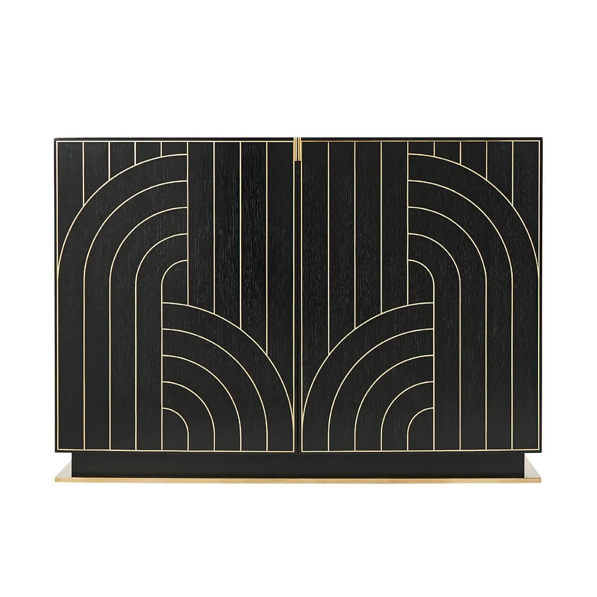 An Art Deco style brass inlaid ebonized oak buffet sideboard. Inspired by high-style art deco designs of the 1920s, the bowfront cabinet is raised on a stepped brass finish base.

Dimensions: 48