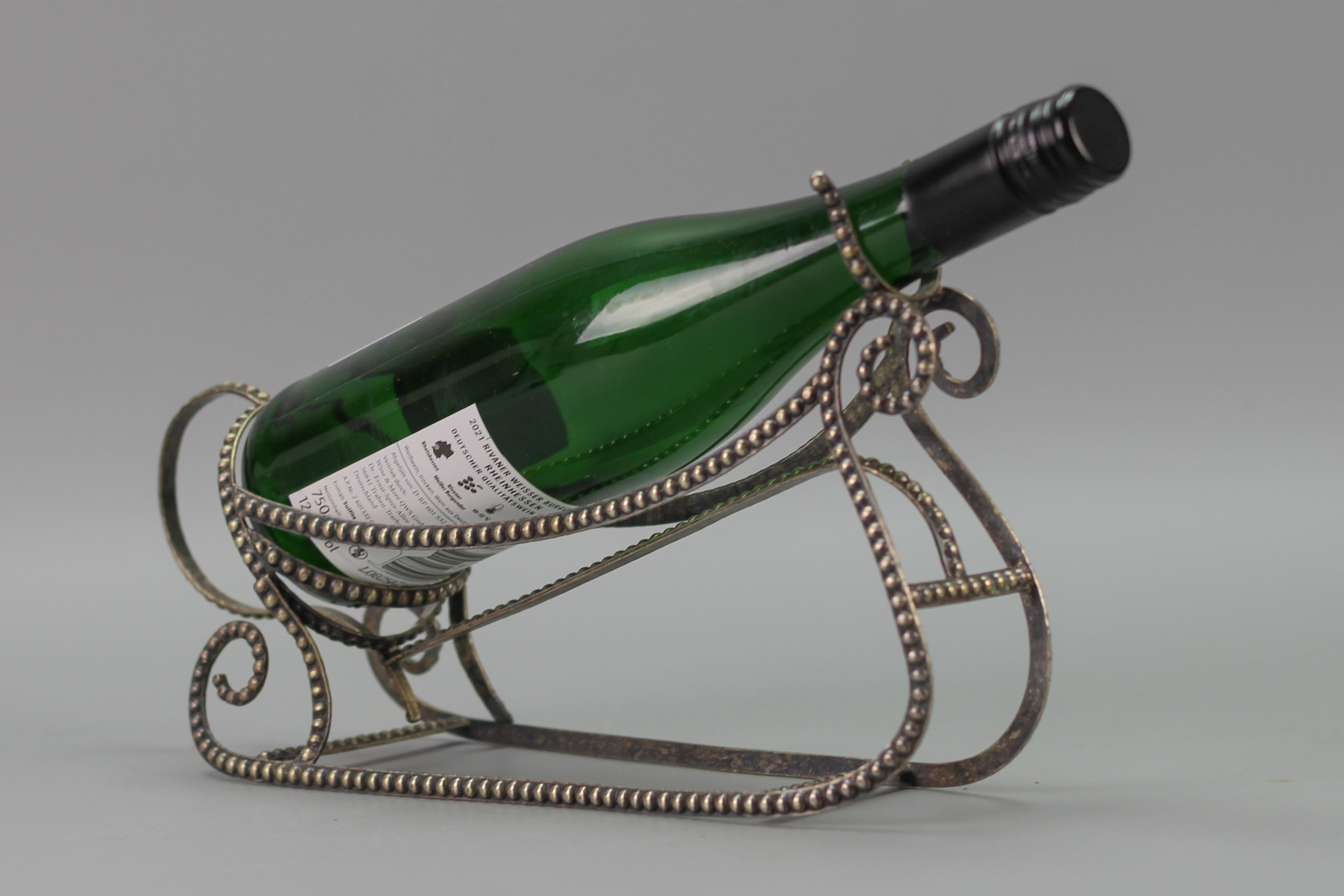 Art Deco Style Brass Silver Color Sleigh-Shaped Bottle Holder from circa the 1950s.
An elegant silver color wine bottle holder made of brass in the shape of a sleigh, throughout decorated with brass beading.
Dimensions: height 18.5 cm / 7.28 in,