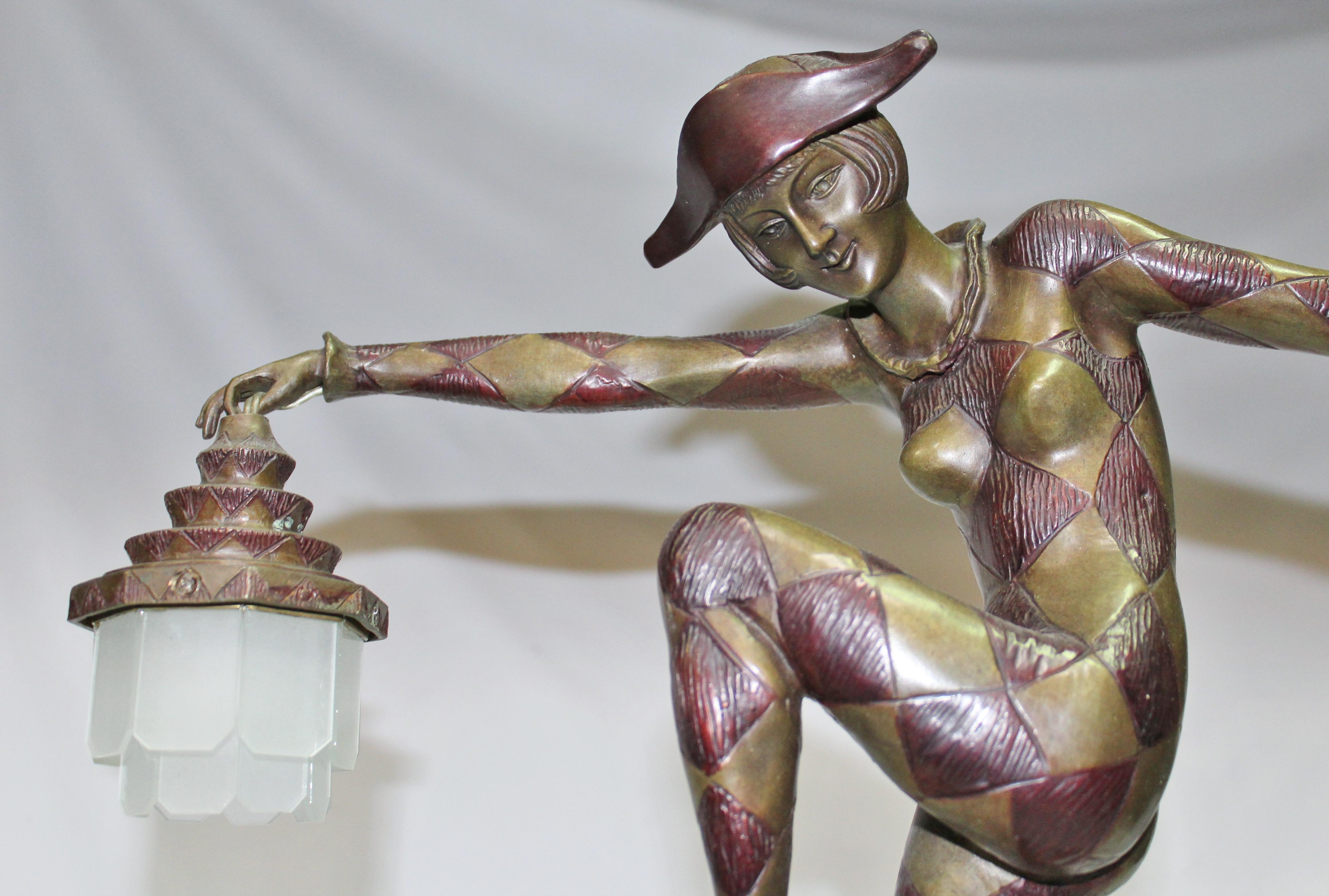 Una conocida Figurita convertida en Lámpara . Fundido en Bronce a la cera perdida y con acabado multipatinado . Pequeños farolillos colgando de cada mano . Acabado y montado sobre una base de mármol Negro Absoluto de 17