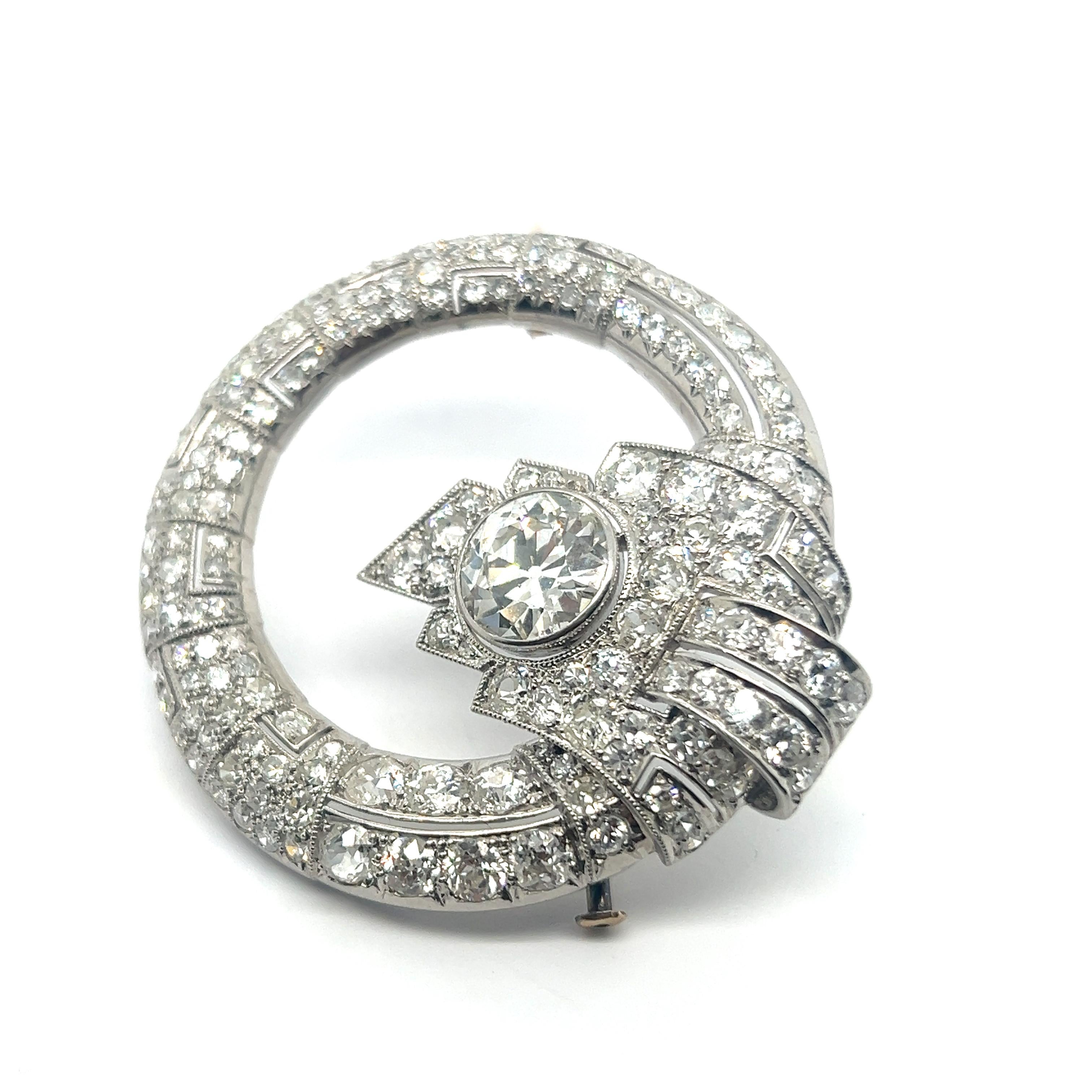 Enter a realm of timeless elegance with an exquisite Art Deco Style brooch in platinum. 

Featuring circular form, this brooch is adorned with 170 diamonds of diverse cuts, embracing a magnificent center stone—an old cut diamond of 3.10 carats with