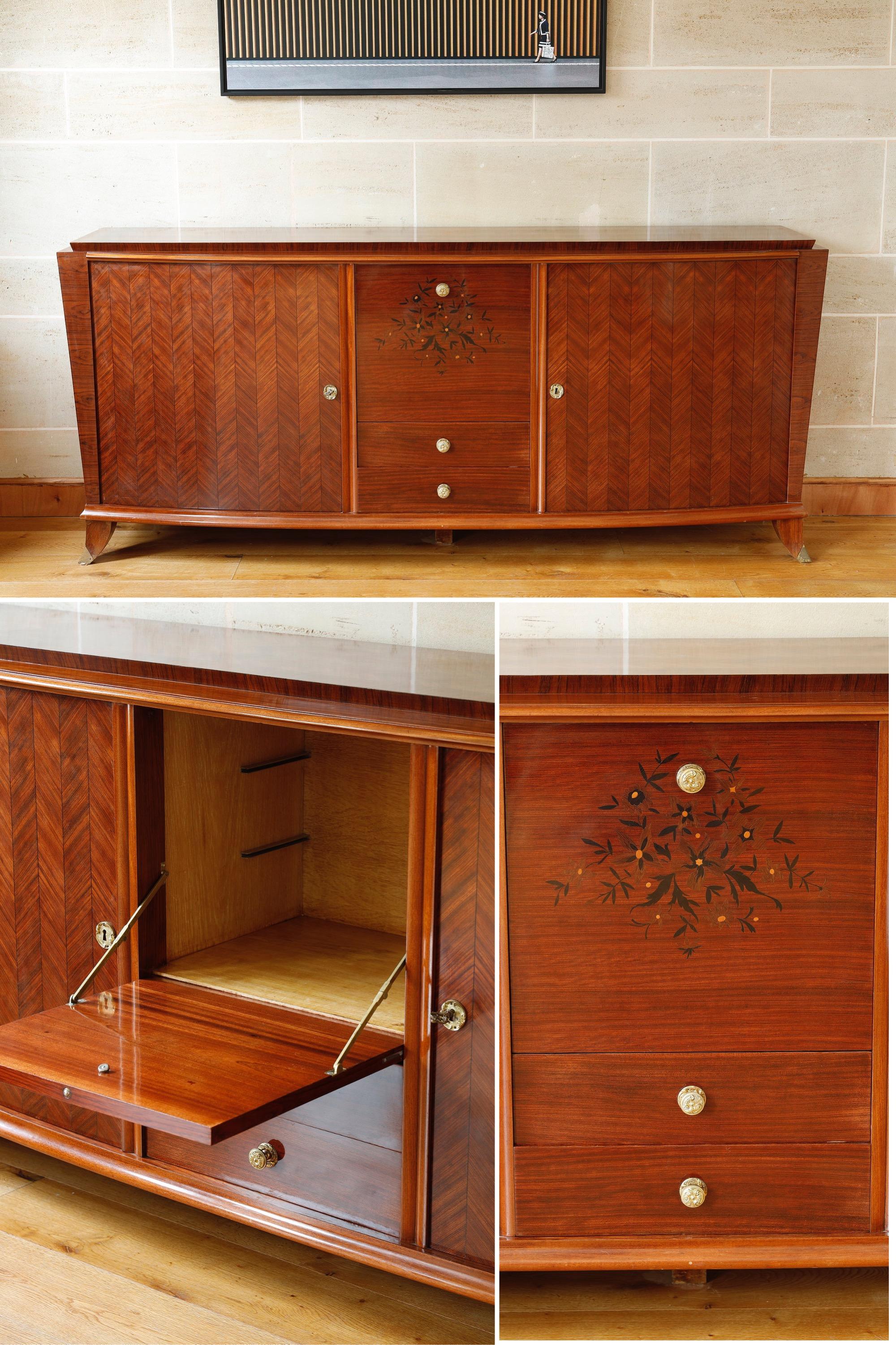 Large sideboard in the taste of Maison Leleu dating from the 1950s and made of alternating rosewood and rosewood veneer in the Art Deco style. It opens on the sides with two large leaves and at the bottom center with two drawers under a flap door