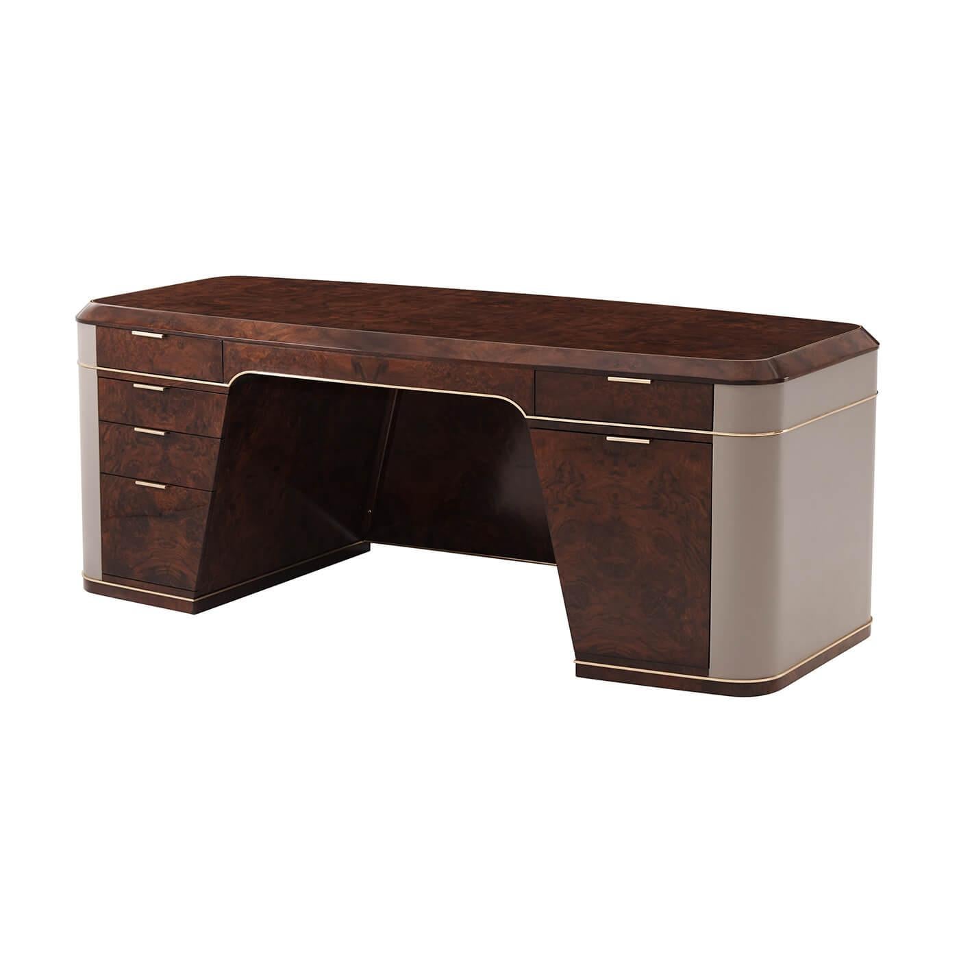 An Art Deco style burl pedestal desk with brass moldings and trim, a wonderful burl walnut veneer to the hull shaped case, with leather paneled wrapped sides and with two frieze drawers with brass handles, the spacious 33