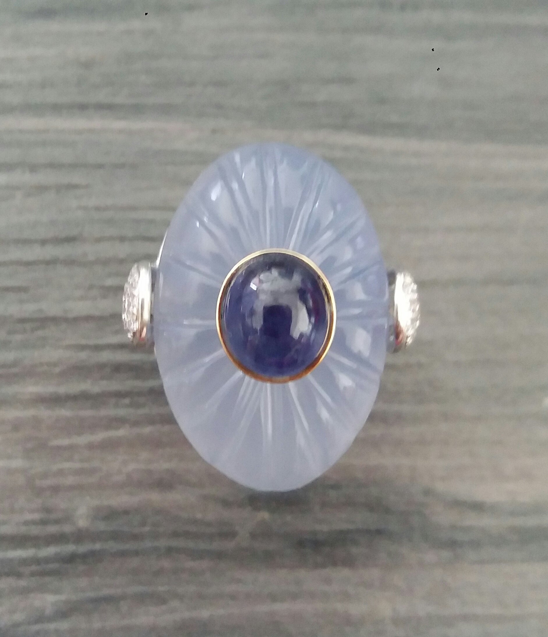 Classic and elegant ring composed of an oval engraved Chalcedony cabochon surmounted by a Blue Sapphire Cabochon set in a 14k yellow gold bezel...The shank  is also in 14k  White Gold with 2 pear shape pave' of 34 full cut diamonds on the sides