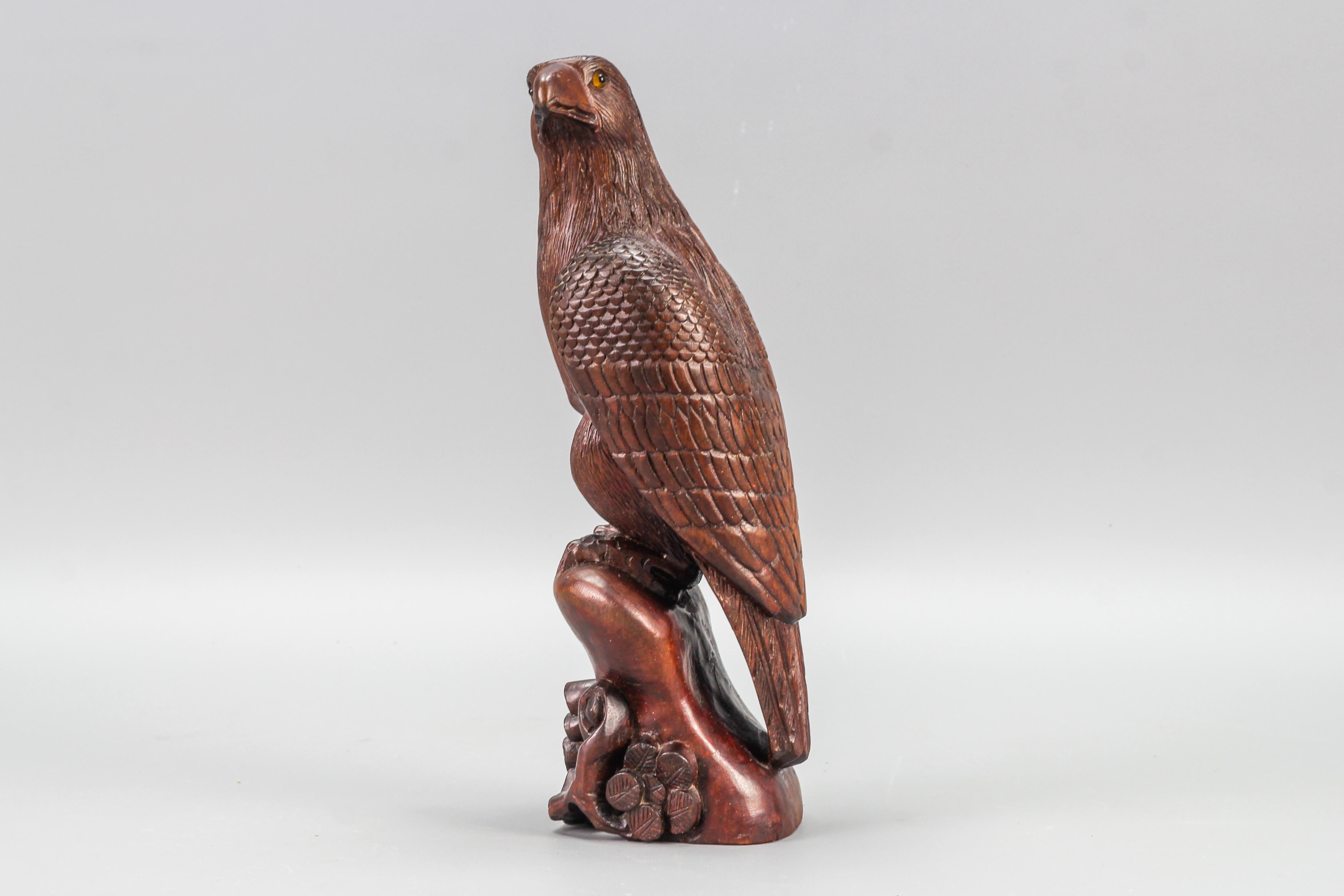 Art Deco Style carved Wooden Eagle sculpture with glass eyes from the 1960s.
This stunning, naturalistically hand carved and brown tinted beechwood eagle figure with glass eyes, perched on a wooden trunk decorated with a leafed branch, would be a