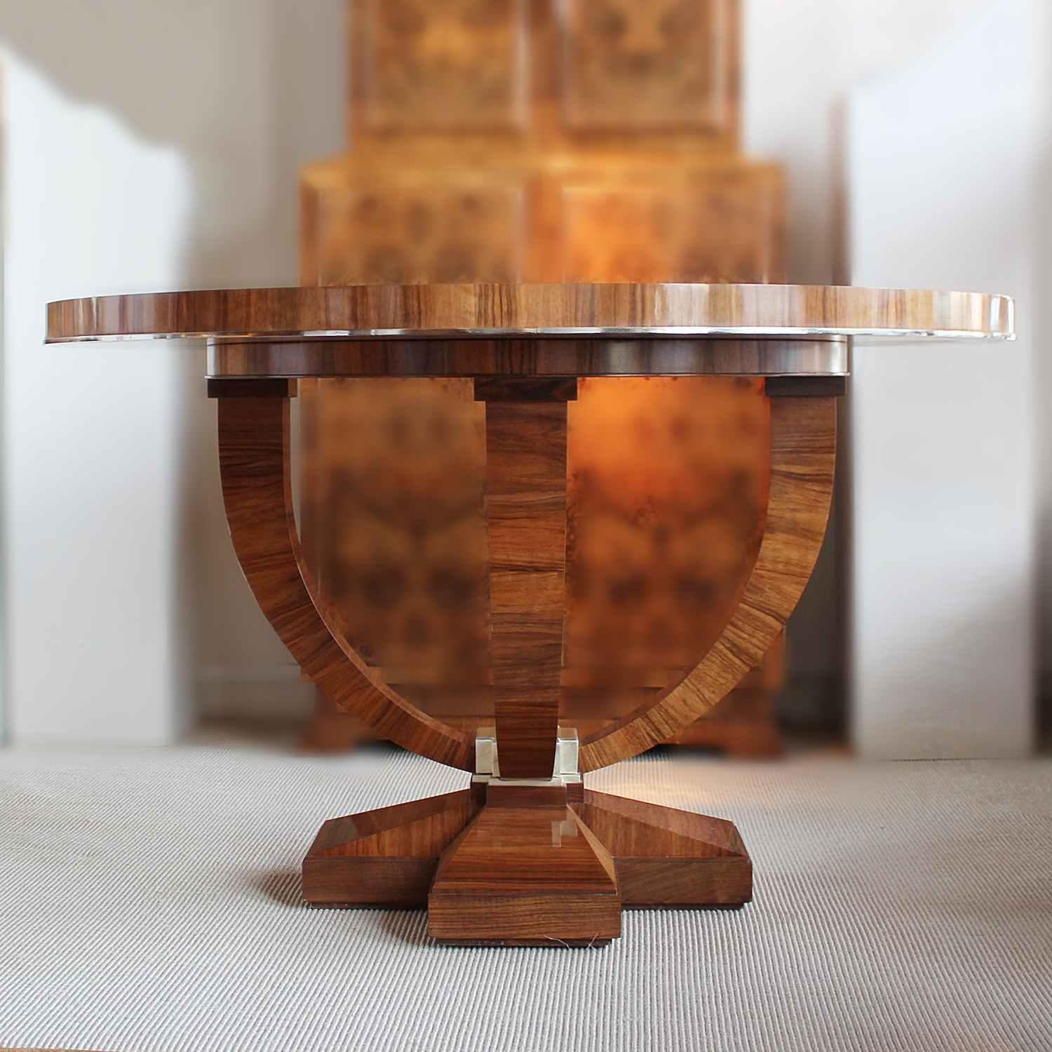 A 20th century Art Deco style centre table. Large circular top of sectioned, figured walnut with metal banding. Set over curved legs on a cross footed base with lacquered wood detail to centre.

    