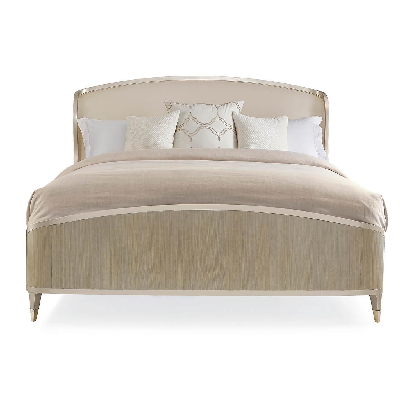 An Art Deco-style champagne shimmer king bed with a shapely silhouette. The elegant bed is crafted with Koto panels in a Champagne shimmer finish. Metal ferrules in Whisper of Gold, cap the legs and add an elegant finishing