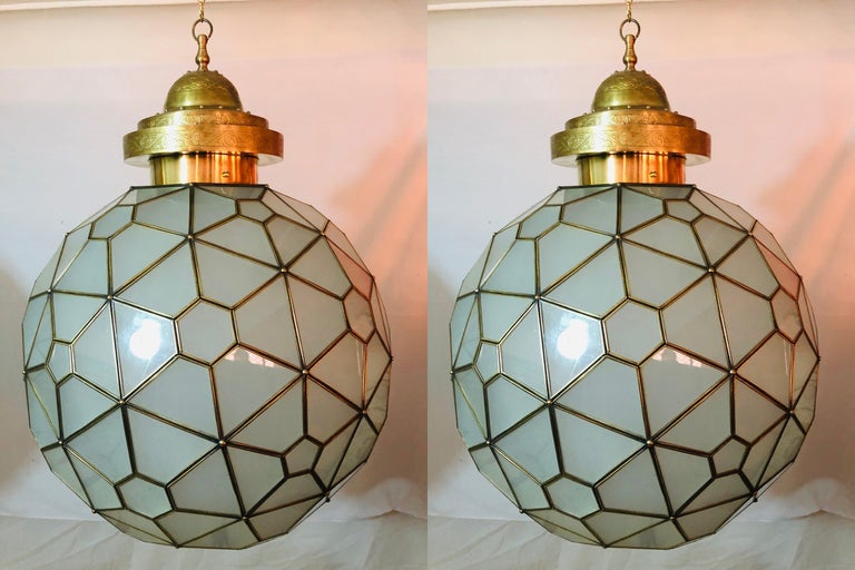 A pair of Art Deco style chandelier or pendant globe in globe shaped made of milk glass and brass.

Light up your room with this stunning handmade pair of Art Deco style globe round form milk glass white chandeliers or lanterns with brass inlay