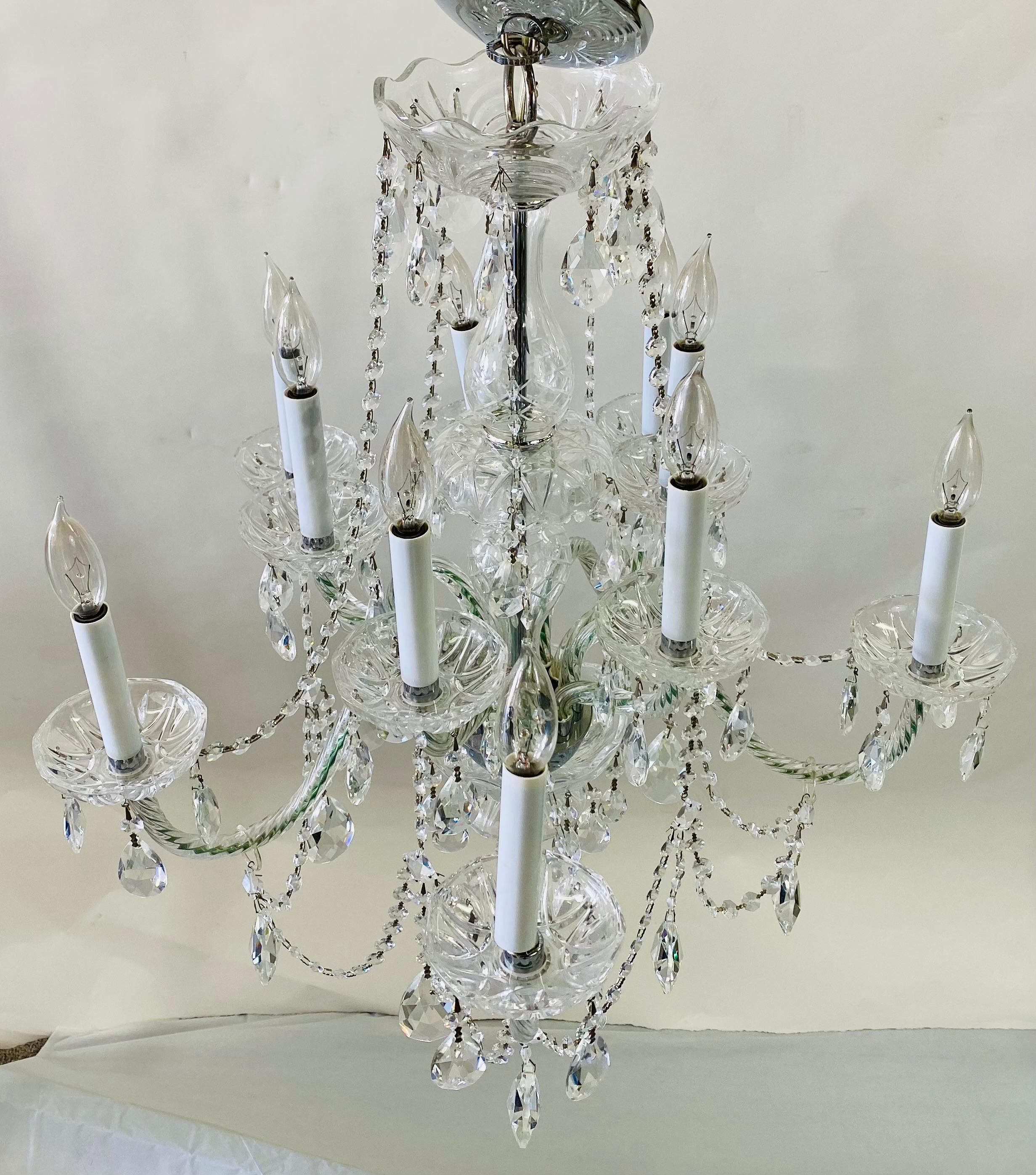 An elegant Art Deco crystal chandelier in the manner of Waterford. The chandelier features 10 arms and take 10 candelabra bulbs. The finely cut crystal prisms hang from a double bobeche candle drip. This chandelier will  add class and sophistication