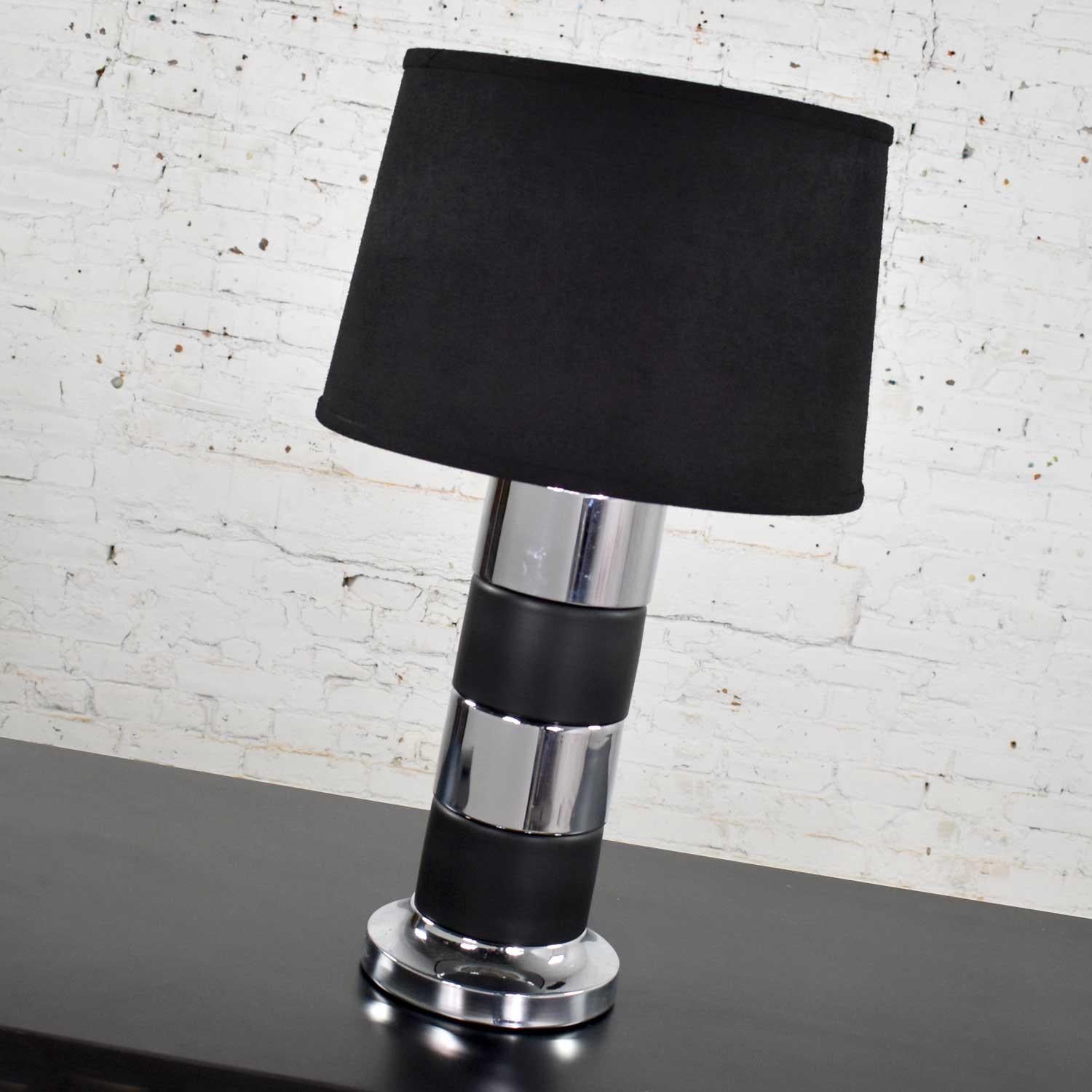 Belle lampe de table cylindrique de style Art Déco avec des bandes horizontales noires et chromées et un abat-jour tambour noir. Cette lampe est dans un état vintage fabuleux. Il a été restauré et recâblé et dispose d'un nouveau store. Bien qu'il