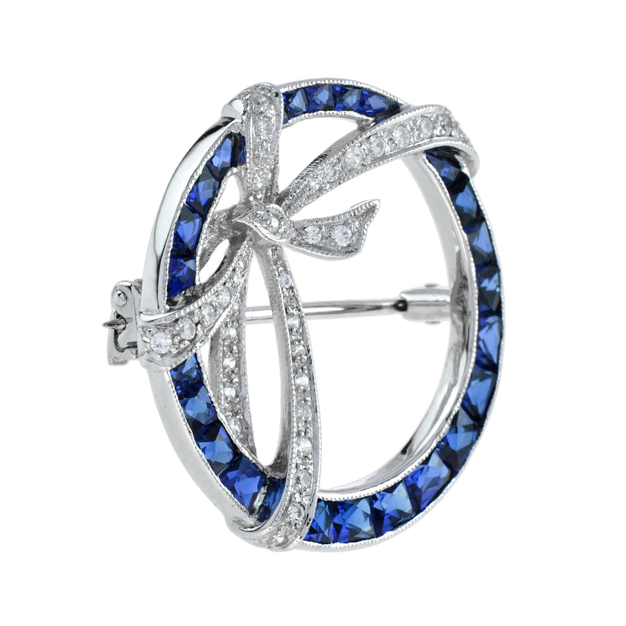 Vintage Art Deco design brooch pin set with round cut diamonds and French cut sapphires. Designed in 14k white gold with a ribbon circle motif, hinged pin brooch and catch. 

Information
Metal: 14K White Gold
Width: 28 mm.
Length: 29 mm.
Weight: