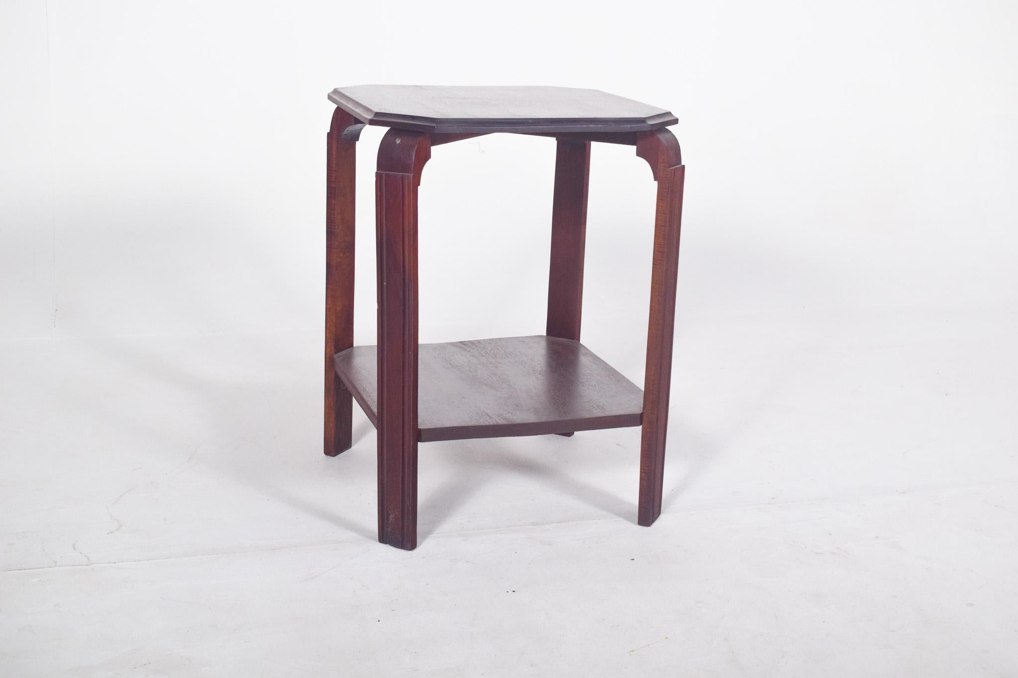 Mesa de centro estilo Deco. Con una parte superior de forma octogonal, está formada por cuatro patas verticales de sección rectangular, con una ligera hendidura decorativa en la parte superior interna de cada pata. Las patas conectan la parte