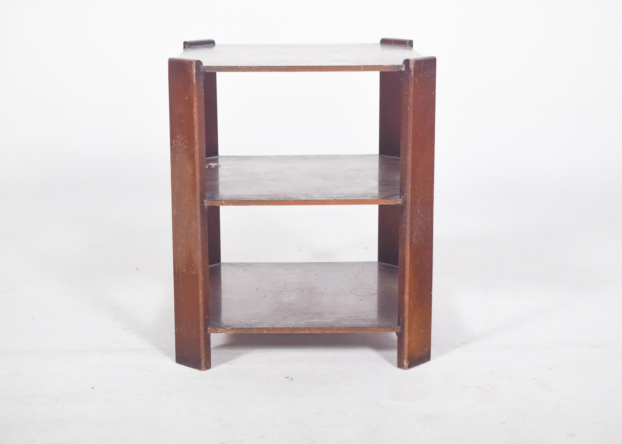 Mesa de centro Deco. Con parte superior, estante central y base inferior, todo en madera con acabado barnizado oscuro. Los laterales están formados por listones verticales planos, de un grosor más robusto, que actúan como soportes estructurales y