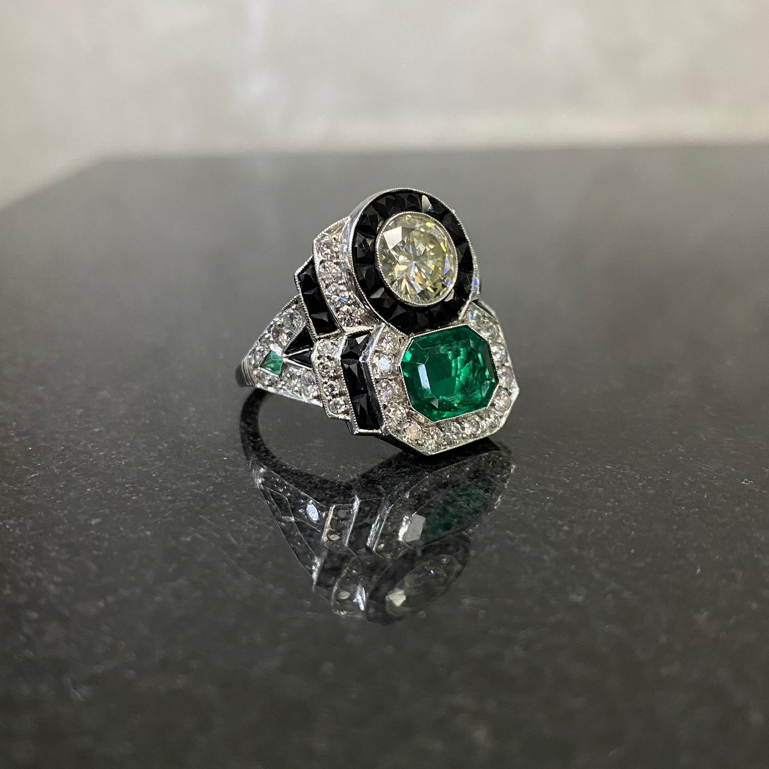 Vintage Colombian Emerald, Diamond and Onyx Bypass Cocktail Ring in Platinum, 1990s. This jewel of Art Deco inspiration features a vivid green Colombian emerald and a Transitional round brilliant-cut diamond, in a stylized bypass ring that combines