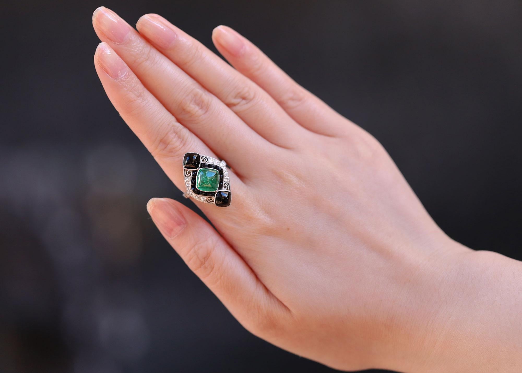 Centered by a lush, green cabochon Colombian emerald along with a bevy of sleek black onyx, this Art Deco inspired cocktail ring is a mesmerizing treasure. Hand crafted of platinum with fine milgrain details and a touch of filigree, a faithful