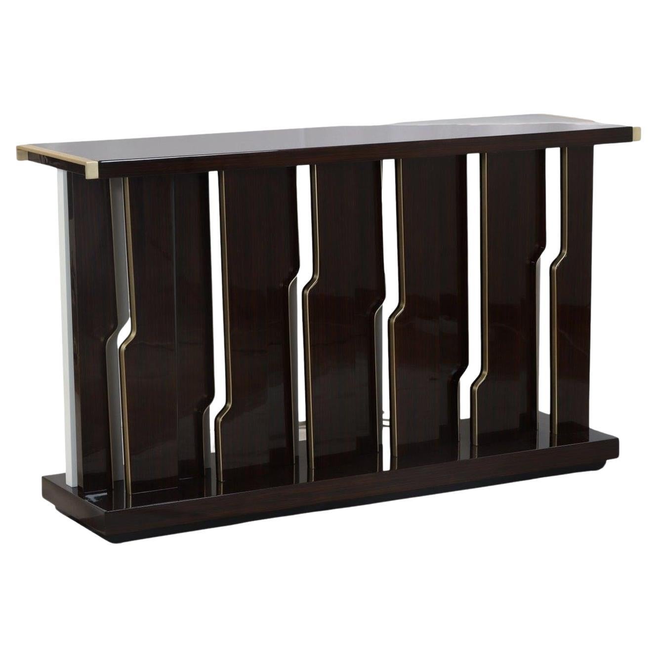 This dramatic and modern console table is a masterful blend of rich wood and metallic accents. The entire piece is crafted from ebony wood with a modern finish that gives it a deep, almost black tone. The table's most distinctive feature is its