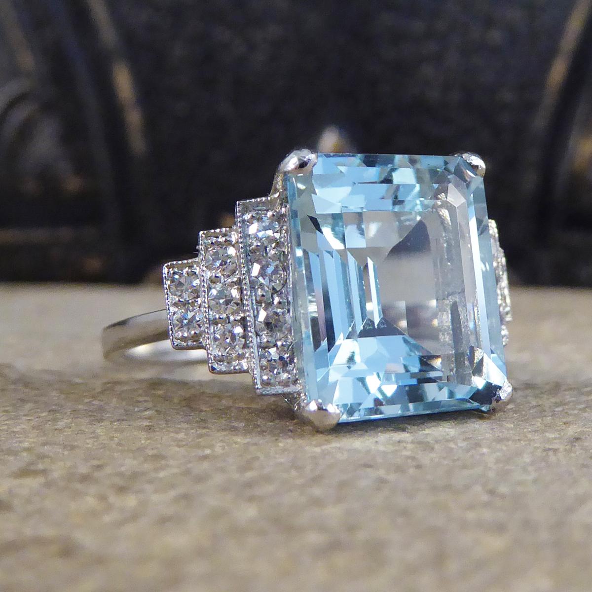 This absolutely stunning ring features a mesmerising 5.50ct Emerald Cut Aquamarine. On either shoulder sit a horizontal pyramid of brilliant cut Diamonds, from closest to the Aqua leading to three then two Diamonds adding sparkle to an already