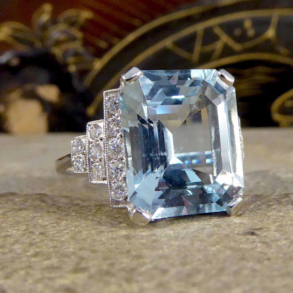 This absolutely stunning ring features a mesmerising 9.00ct bright and beautiful Emerald Cut Aquamarine. On either shoulder sit a horizontal pyramid of brilliant cut Diamonds, closest to the Aqua are five stone, down to three then two Diamonds