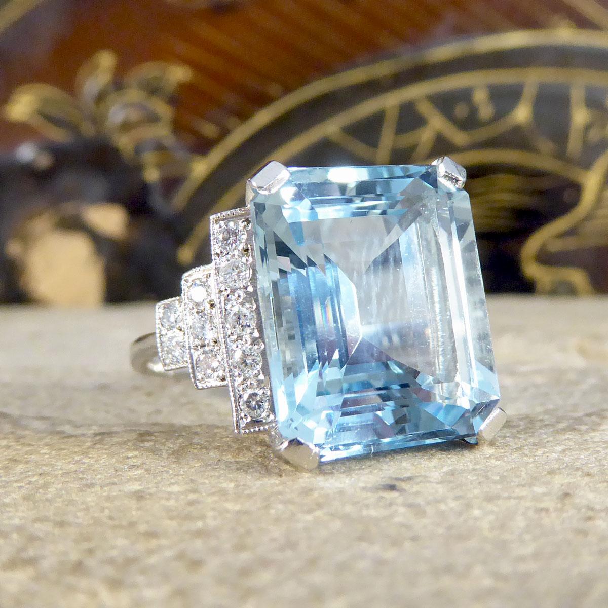 This absolutely stunning ring features a mesmerising 9.15ct bright and beautiful Emerald Cut Aquamarine. On either shoulder sit a horizontal pyramid of brilliant cut Diamonds, closest to the Aqua are five stone, down to three then two Diamonds