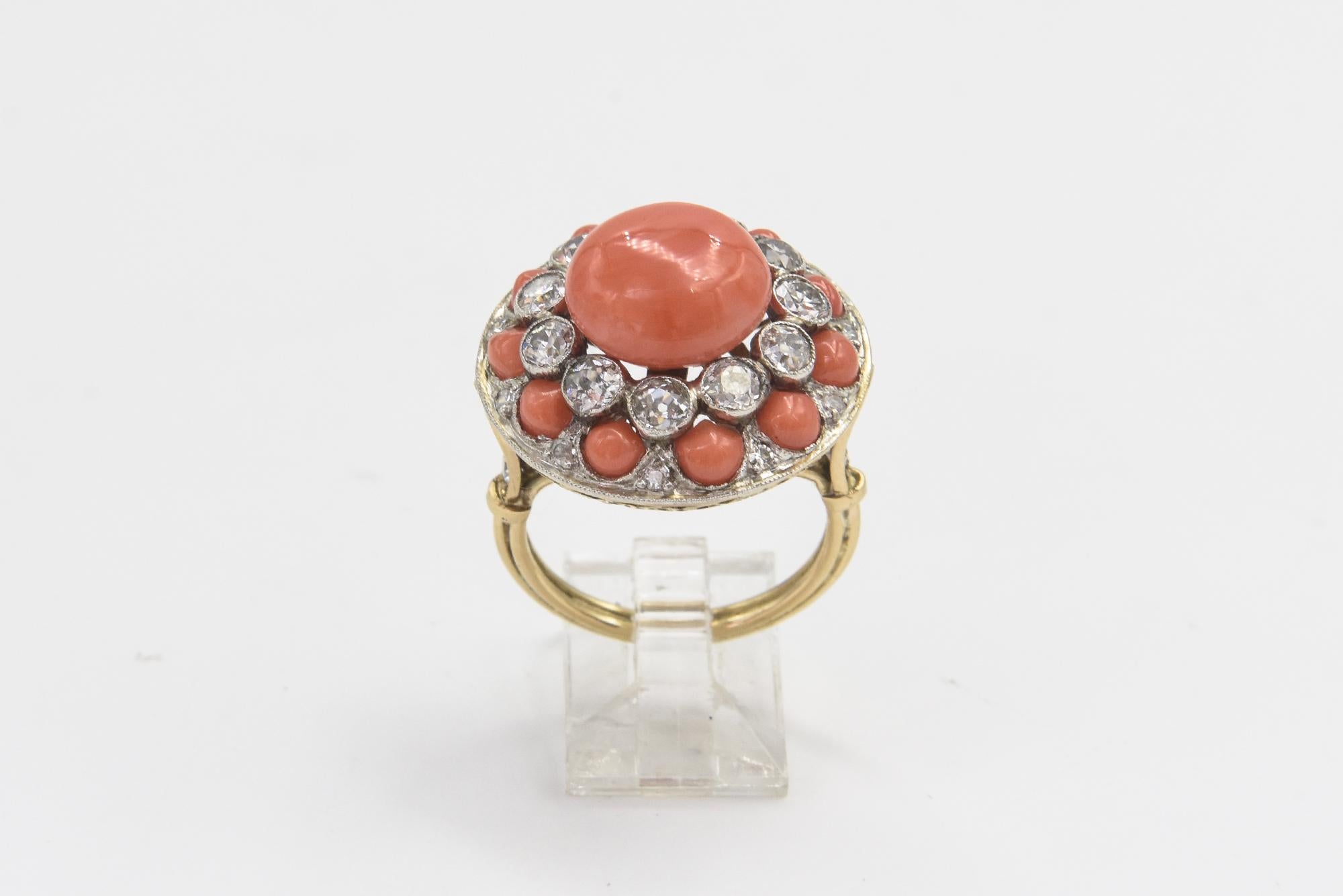 Wunderschön gearbeiteter Korallenring im Art-Deco-Stil mit einer knopfförmigen Koralle in der Mitte, umgeben von 11 eingefassten  - .20 Karat Diamanten, die abwechselnd von einem kleineren Diamanten und einem Cabochon aus Koralle umrahmt werden.  