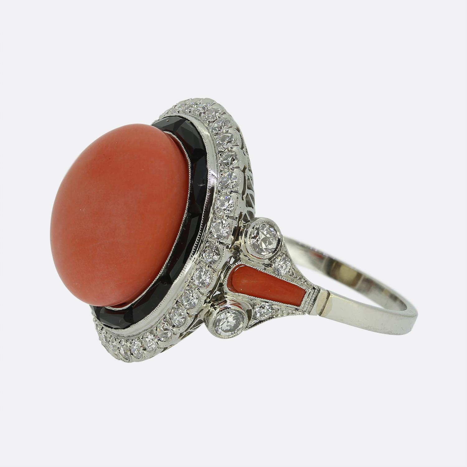 Here we have a chic and stylish coral, onyx and diamond cluster ring. The focal point of the ring is a large button shaped coral at the centre of the face which is surrounded by 10 calibrated onyx stones and 31 round brilliant cut diamonds around