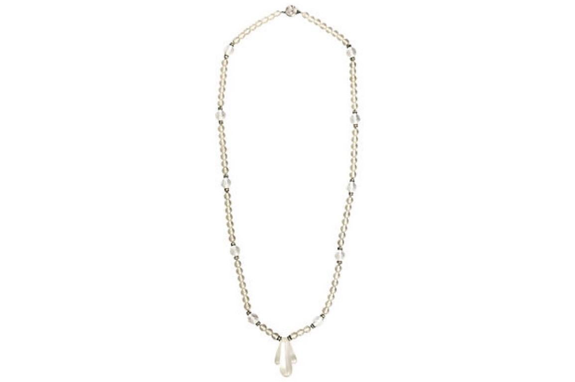 Collana di cristalli in stile déco con sezione centrale scolpita su un filo di perle di cristallo smerigliato con azioni sfaccettate e rondelle di cristallo. La collana termina con una chiusura a pressione. La chiusura è contrassegnata da una H