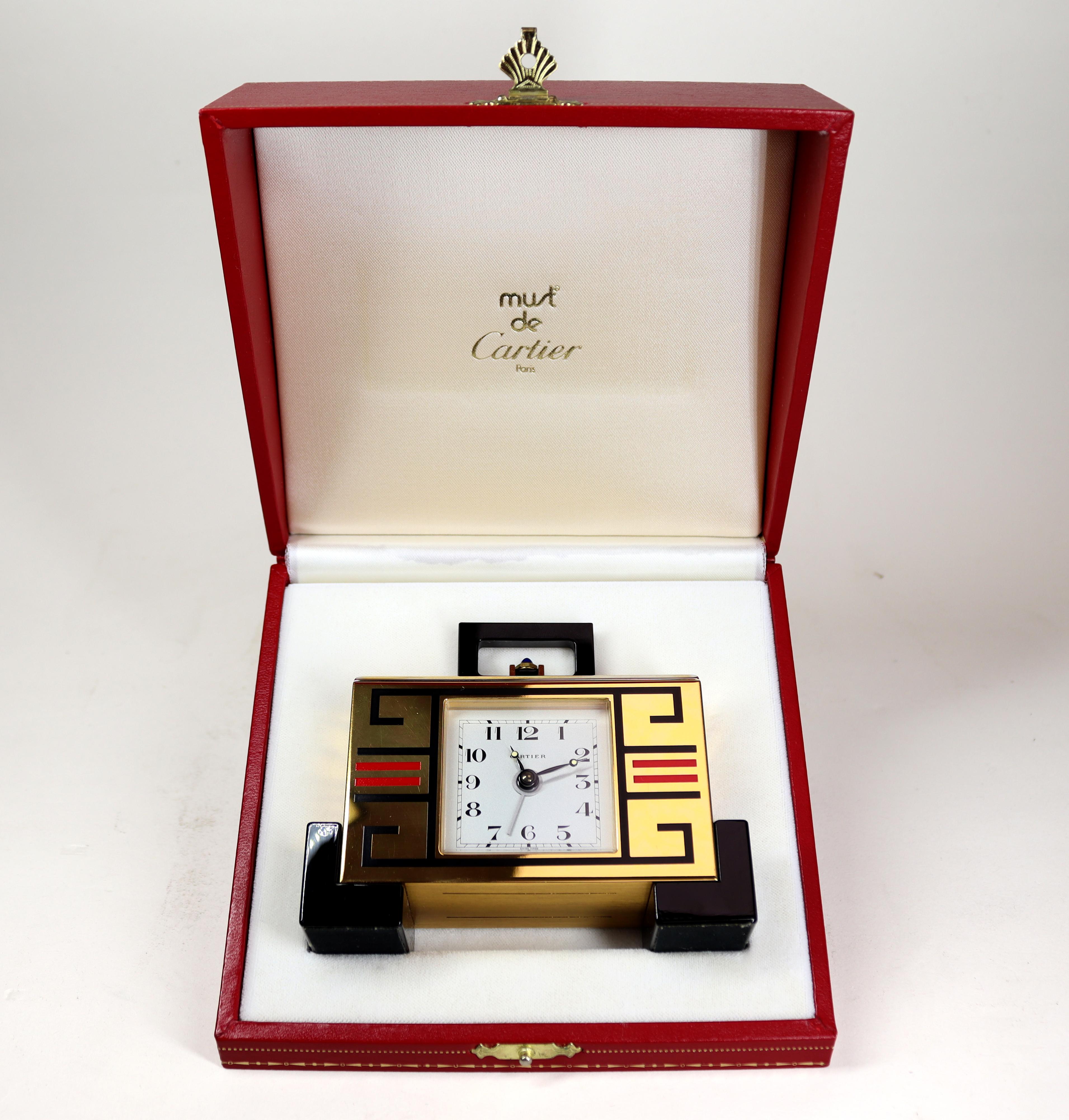 An exceptional alarm clock by Cartier in an Art Deco style case of gilt metal and enamel with a white Arabic dial with luminised hands with cabochon sapphire setting nuts and alarm button. The Swiss made quartz movement is battery powered.

This