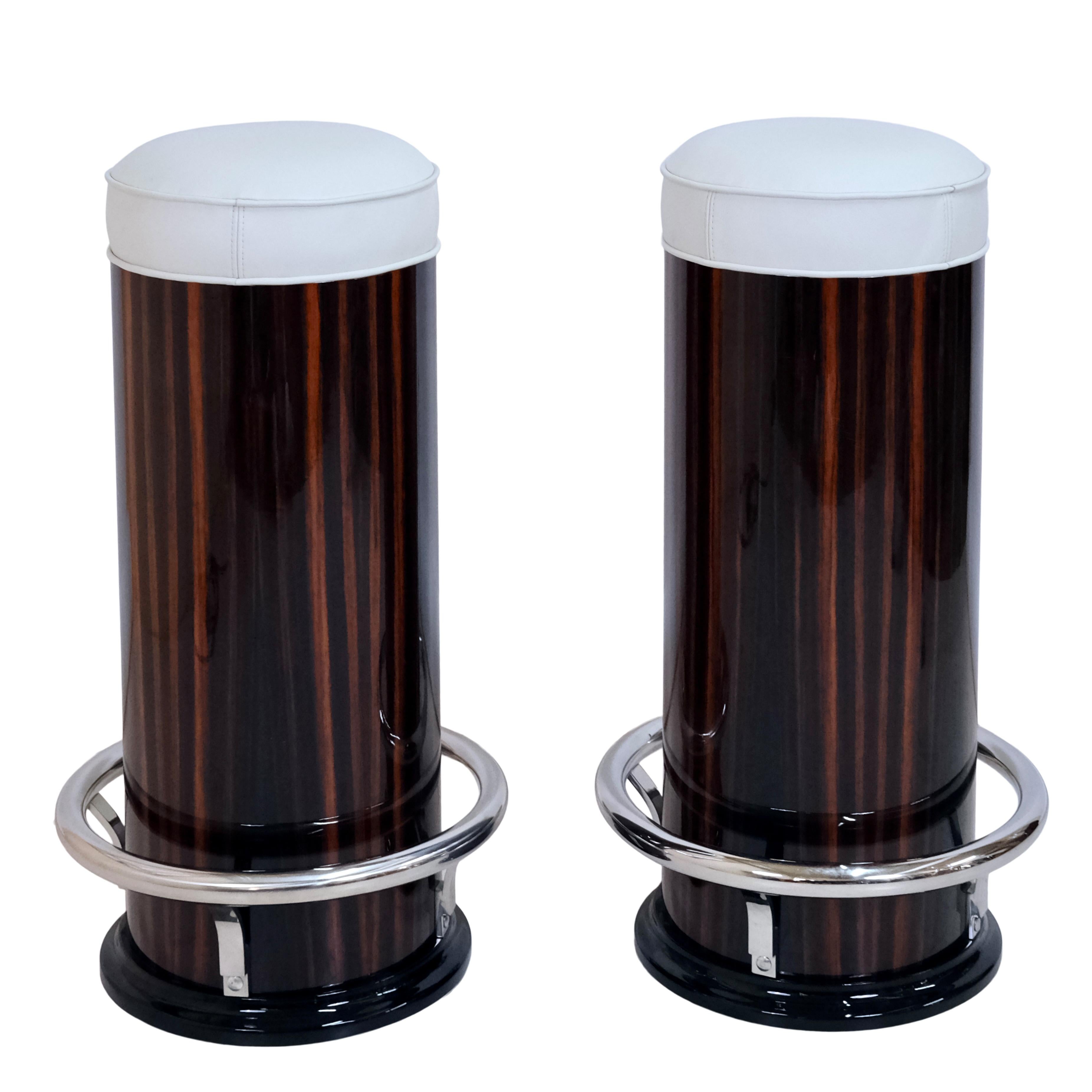 A pair of pillar-shaped bar stools

Macassar veneer, high gloss lacquer finish with black lacquer accents
Chrome-plated metal appliqués
Upholstered seat, real leather

Made in the Art Deco style
Made in Germany

Dimensions, per