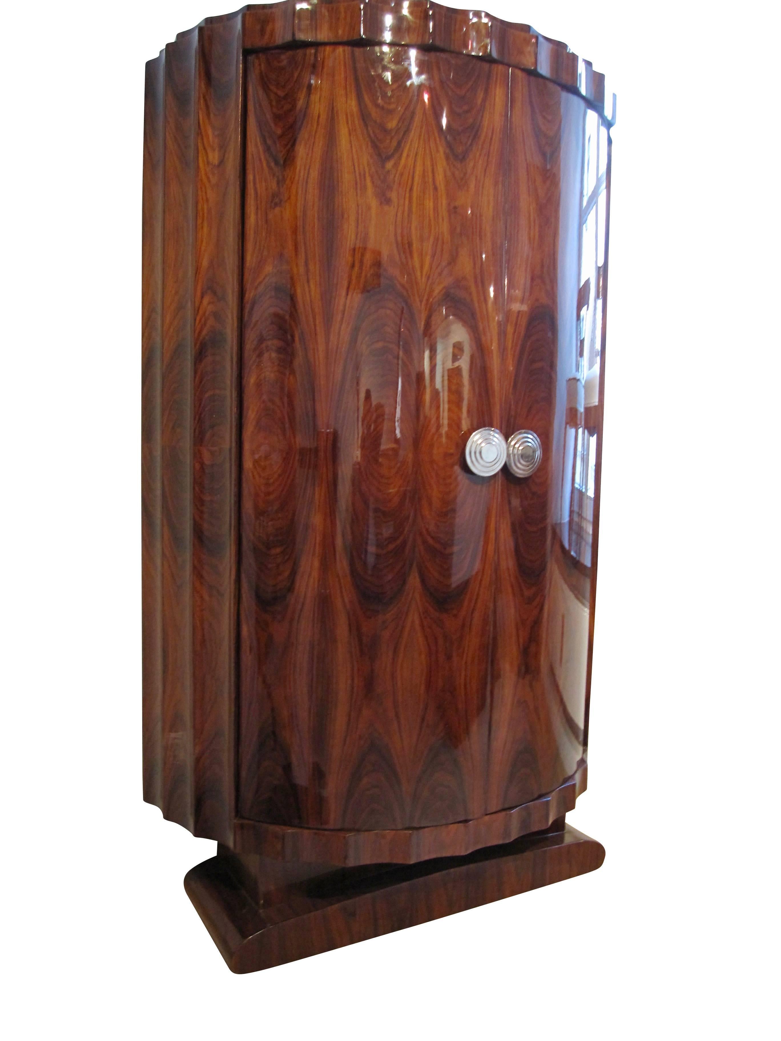 Very special and architecturally interesting demi-lune armoire in Ar Deco Style from France of the 1970s.
Flutet cornice and base with Rosewood (East Indian Palisander) veneer on the in- and outside. Three shelves inside to take out. Beautiful
