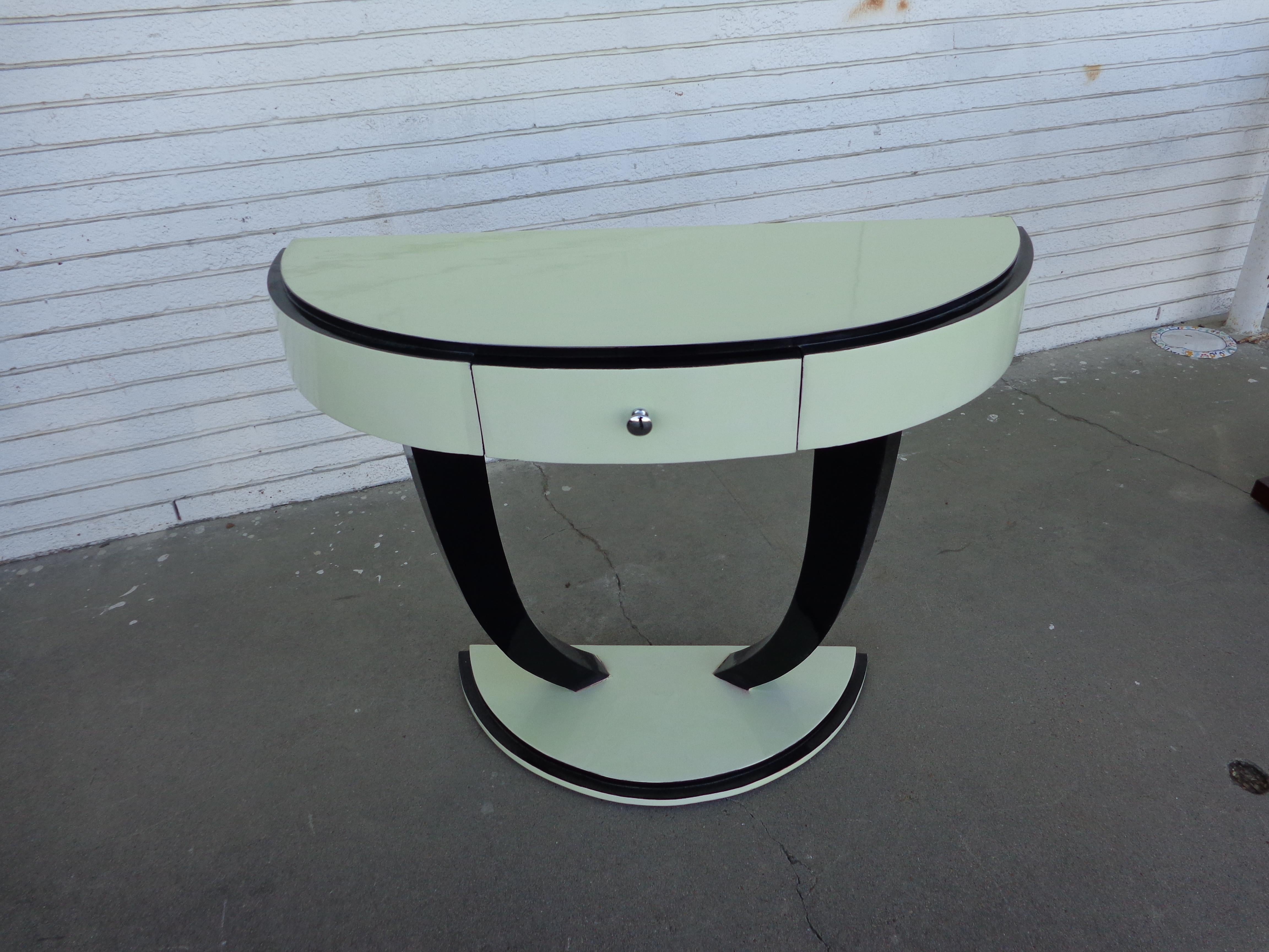 Art Deco style demilune console table

Petite pedestal console lacquered in off-white and black. One drawer with nickel pull.

