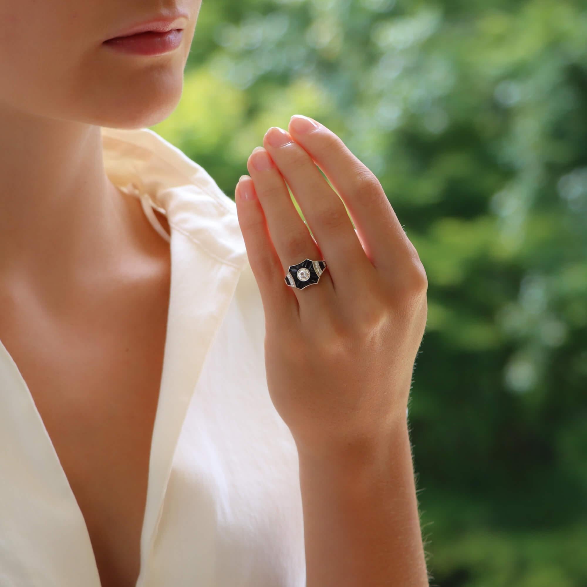 A beautiful diamond and onyx target ring set in platinum. This unique piece centrally features a sparkly round brilliant cut diamond which is surrounded by a halo of calibre-French-cut onyx. The central target leads to tapered shoulders which are