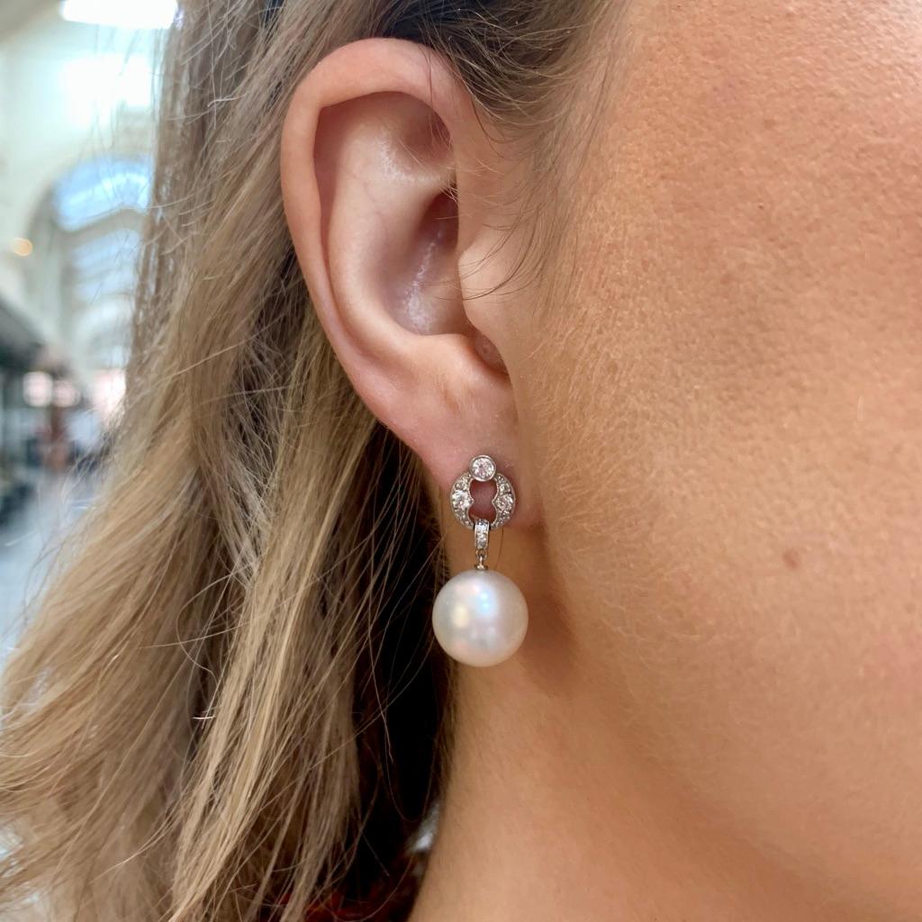  A beautiful pair of vintage Art Deco style pearl and diamond drop earrings set in platinum.

Each earring is firstly composed of a circle motif, set throughout with old mine cut diamonds. From this motif hangs a large south sea white pearl which
