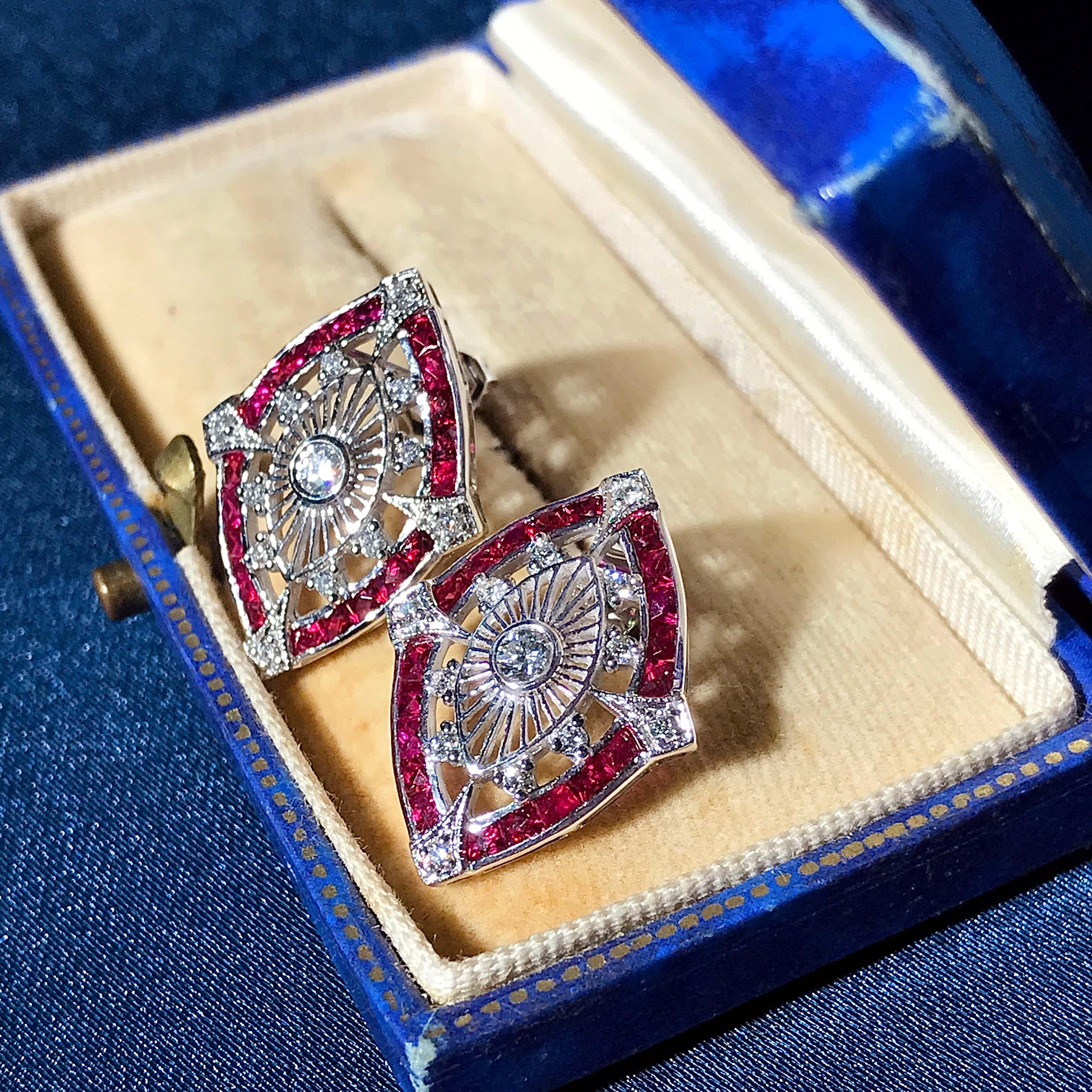 A stunning pair of stud earrings. They are typical of the Art Deco period inspired earrings with the spider web design that holds the round shaped diamond in the center of each earring. Around the edge are French cut rubies with milgrain detail.