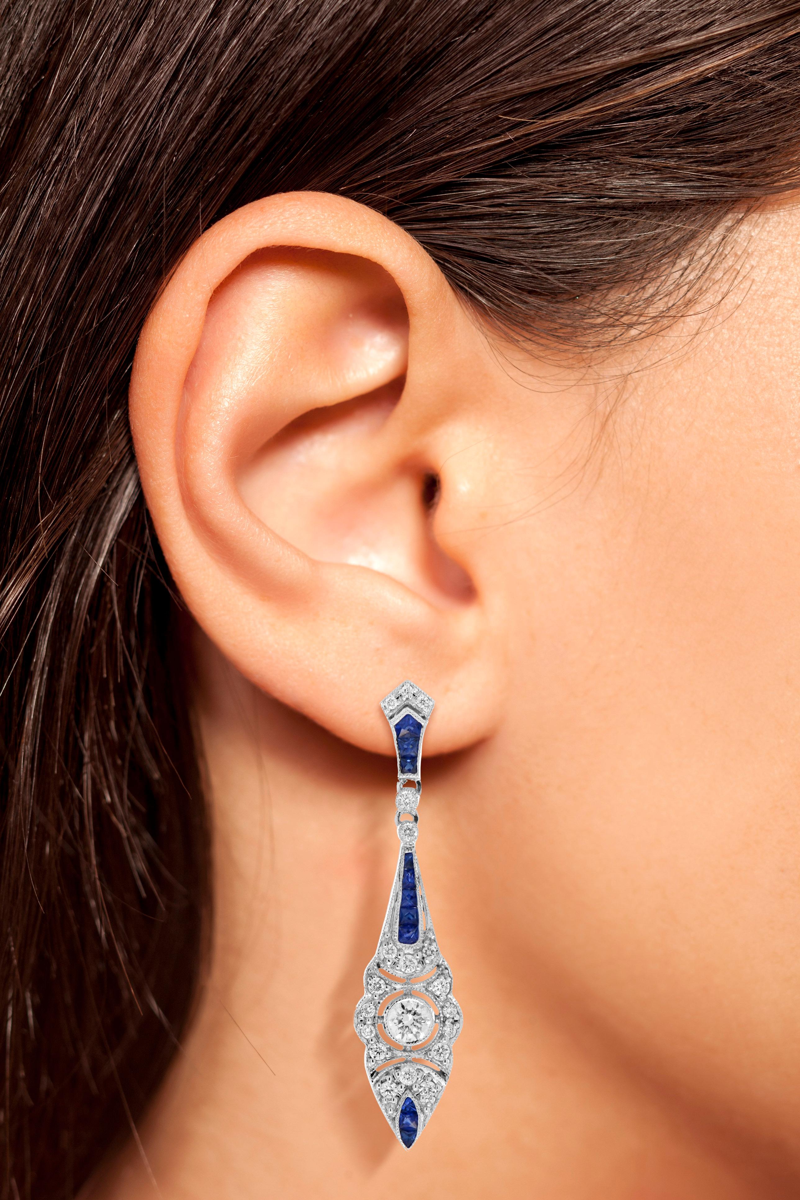 These eye-catching Art Deco-style earrings are hand-crafted in 18k white gold with an intricately detailed geometric design. At the center of each earring, a round diamond is set together with a shimmering diamond accent. These settings are