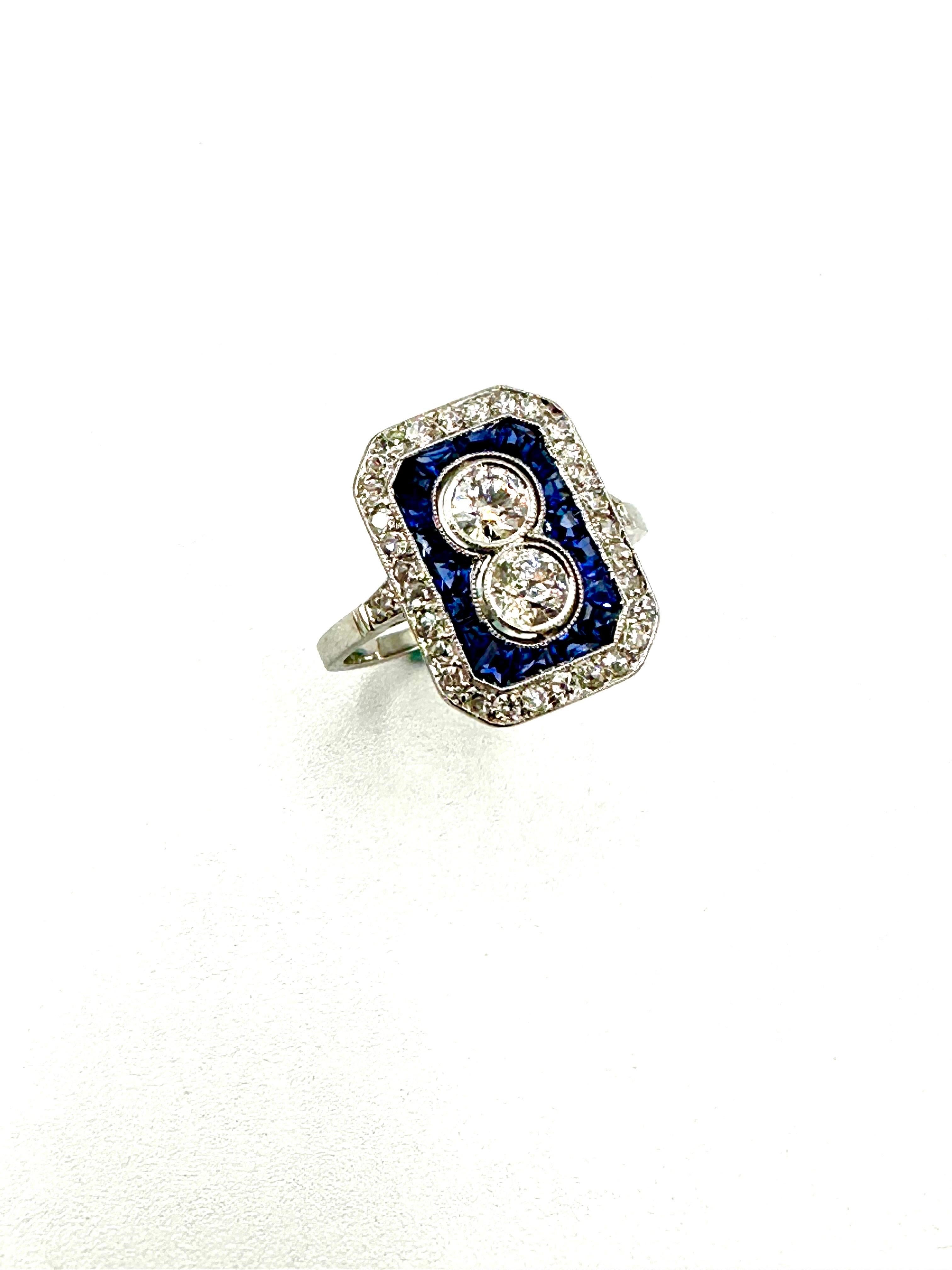 A beautiful Art Deco style Diamond and Sapphire 14 karat white gold fashion ring.  The ring is designed with the two center Diamonds are bezel set with a single row of sapphires, which are surrounded by a single row of Diamonds.  The Diamonds have a