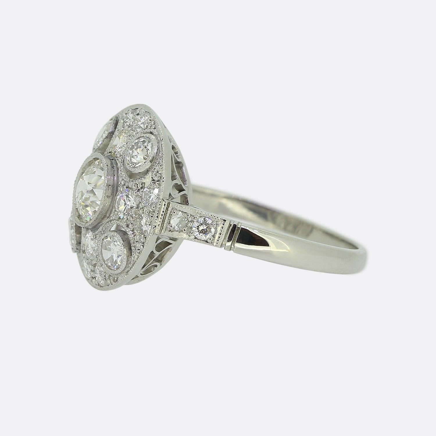 Ecco un anello circolare a grappolo di diamanti di eccellente fattura che rende superbamente omaggio allo stile Art Deco. Al centro della faccia troviamo un diamante rotondo sfaccettato di taglio antico in una raffinata montatura a grana fine, a cui