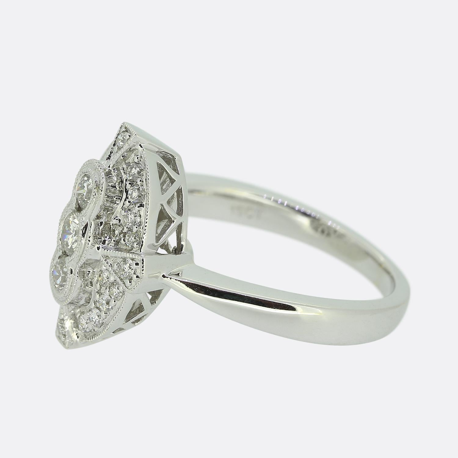 Aquí tenemos un impresionante anillo de estilo Art Déco que rinde un maravilloso homenaje a una época famosa por su precisión y elegancia. Un trío de diamantes redondos de talla brillante se eleva en una formación vertical sobre un fondo lleno de