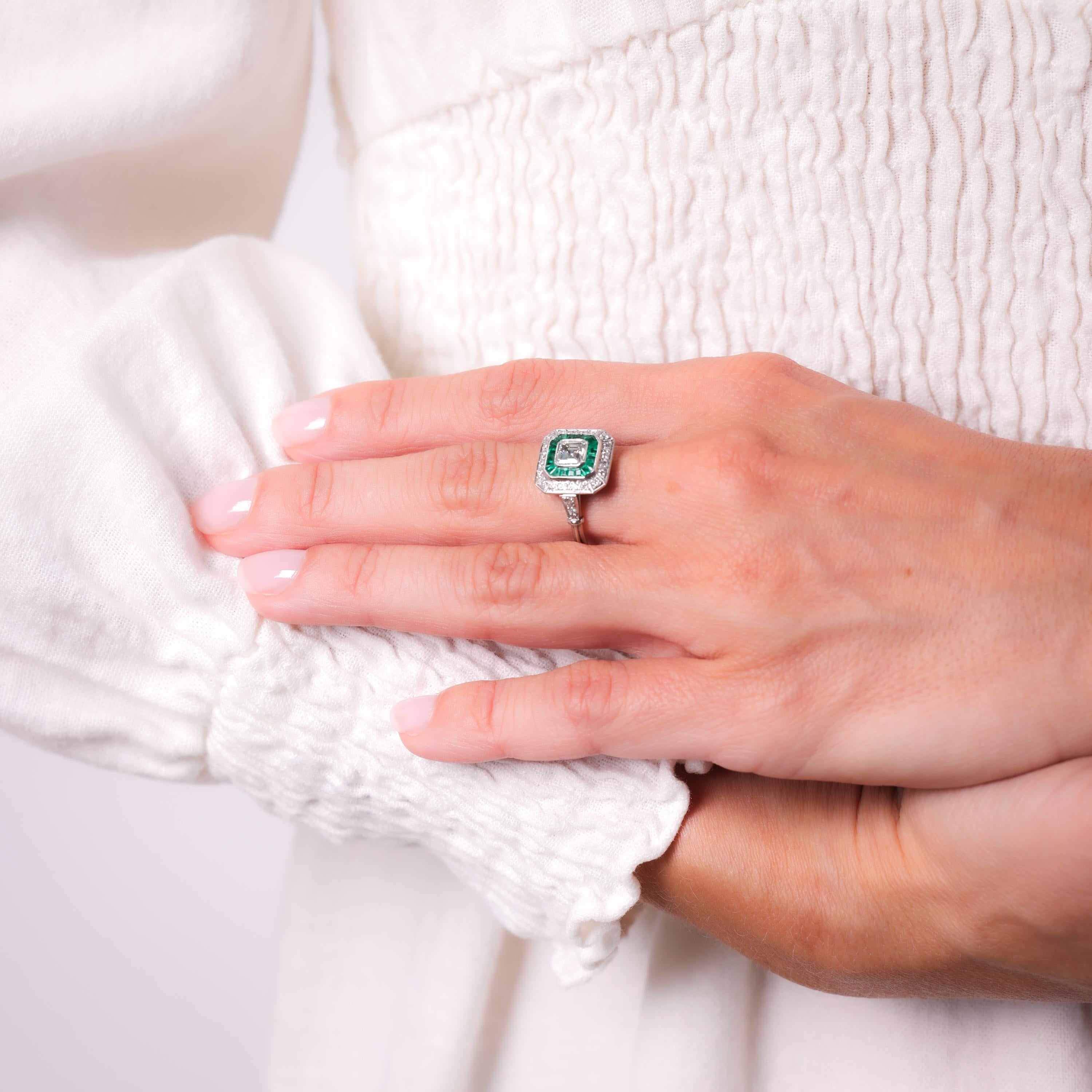 Center Stone: Asscher Cut Diamond 
Weight: Approximately .55 Carat
Color: I
Clarity: VS
Accent Stone: 20 Calibre Cut Emeralds
Weight: Approximately .60 Carats
Accent Stone: 24 Old European Cut Diamonds
Weight: Approximately .50 Carats
Color: